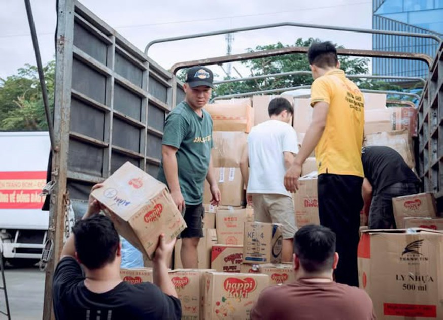 A group of people loading cardboard boxes into the back of a truck