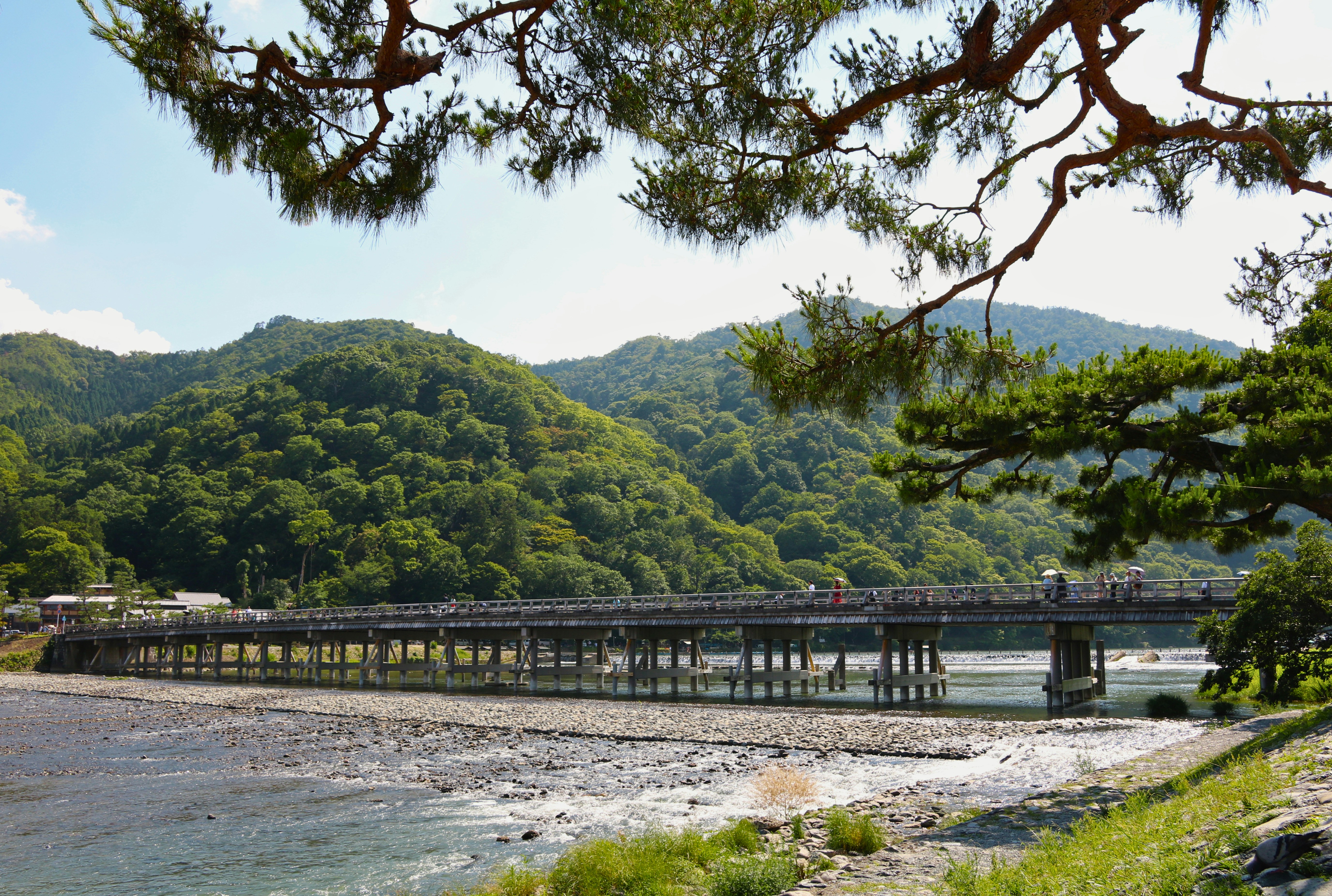 People walking across the Togetsukyo Bridge over the Katsura River in Kyoto