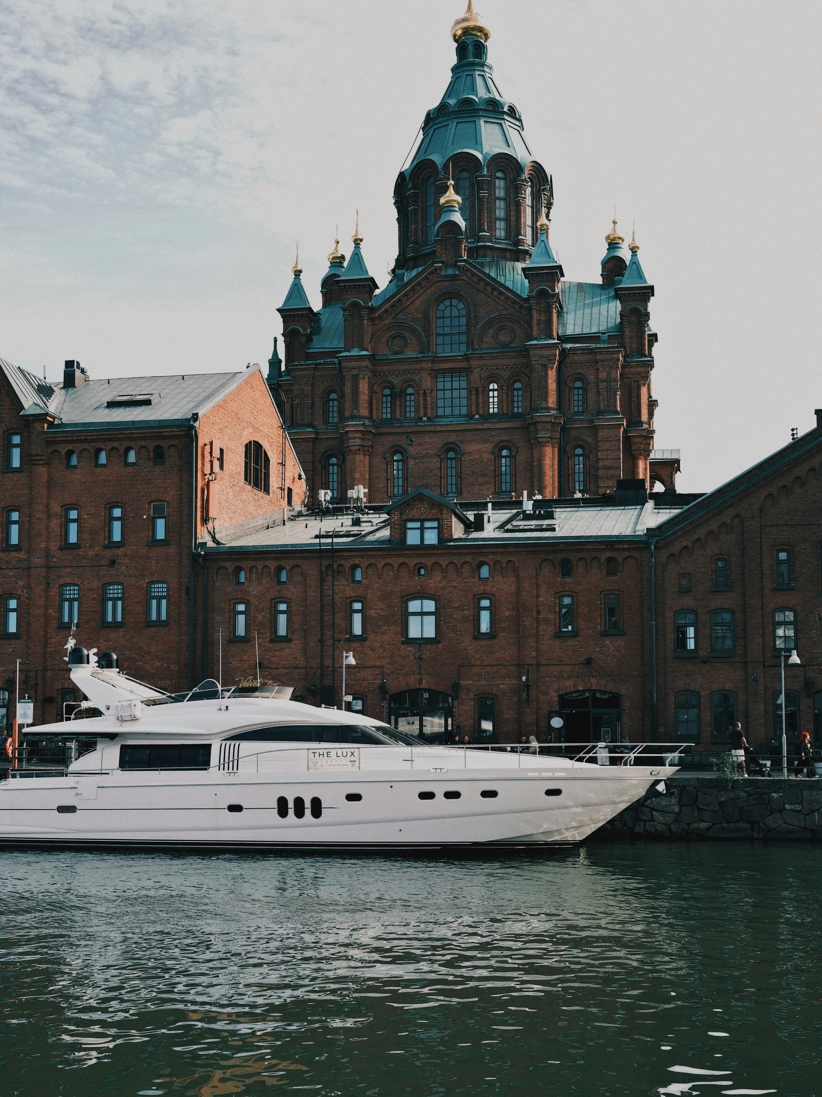 A white yacht moored in front of Uspenski Cathedral in Helsinki