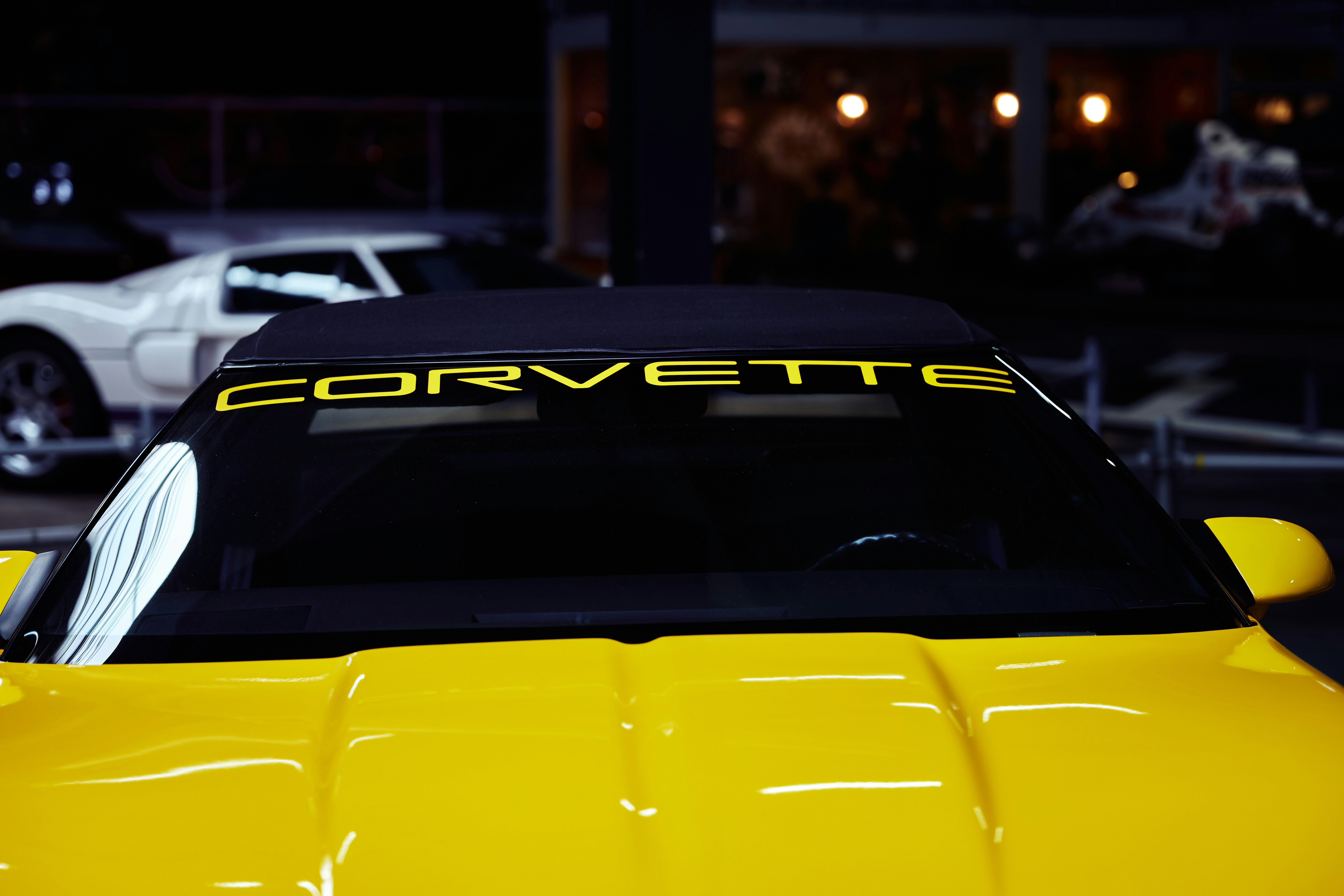 A yellow sports car with a Corvette decal on the windshield