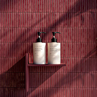 Two pump bottles of shampoo and conditioner on a shelf against red tiles