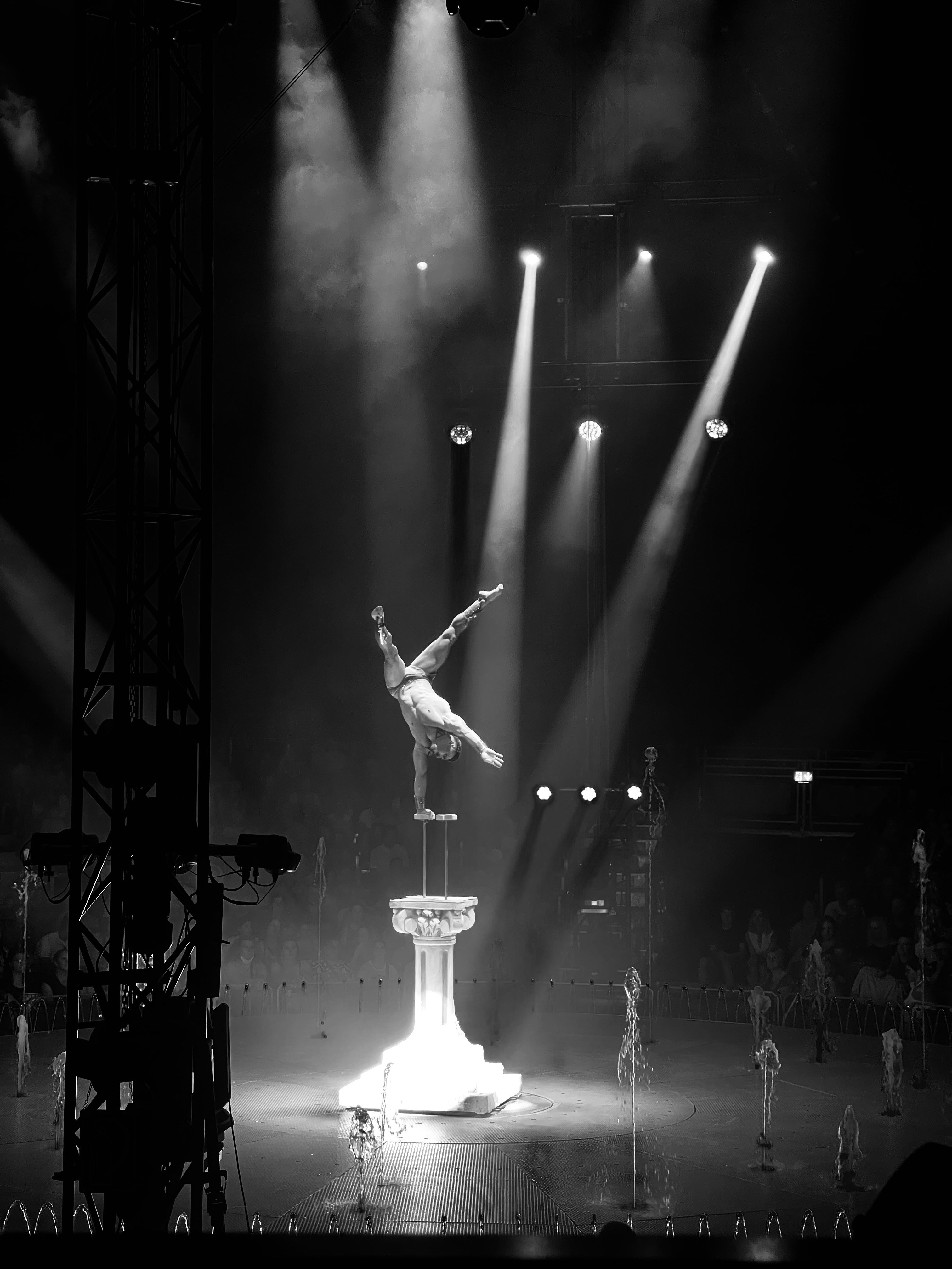 Un artista che si bilancia su una mano su un piedistallo sotto i riflettori luminosi del palco