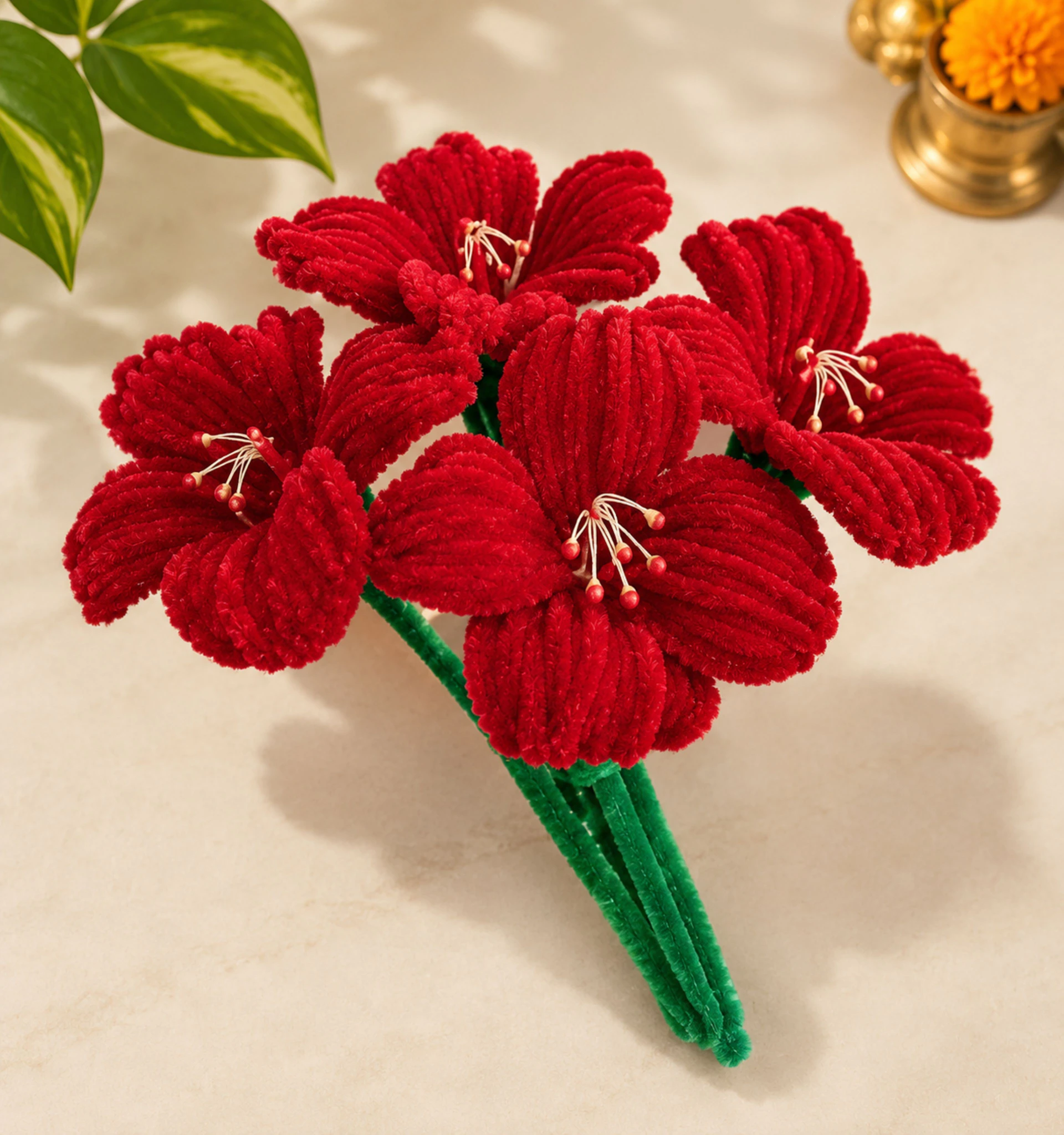 A bouquet of red flowers made from fuzzy pipe cleaners on a table