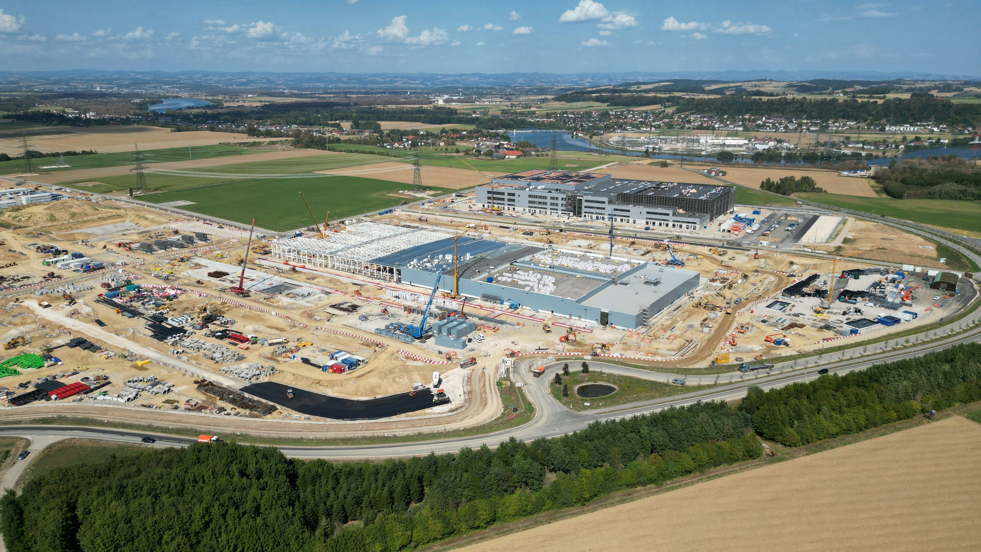 Aerial view of a large industrial construction site with cranes and unfinished buildings
