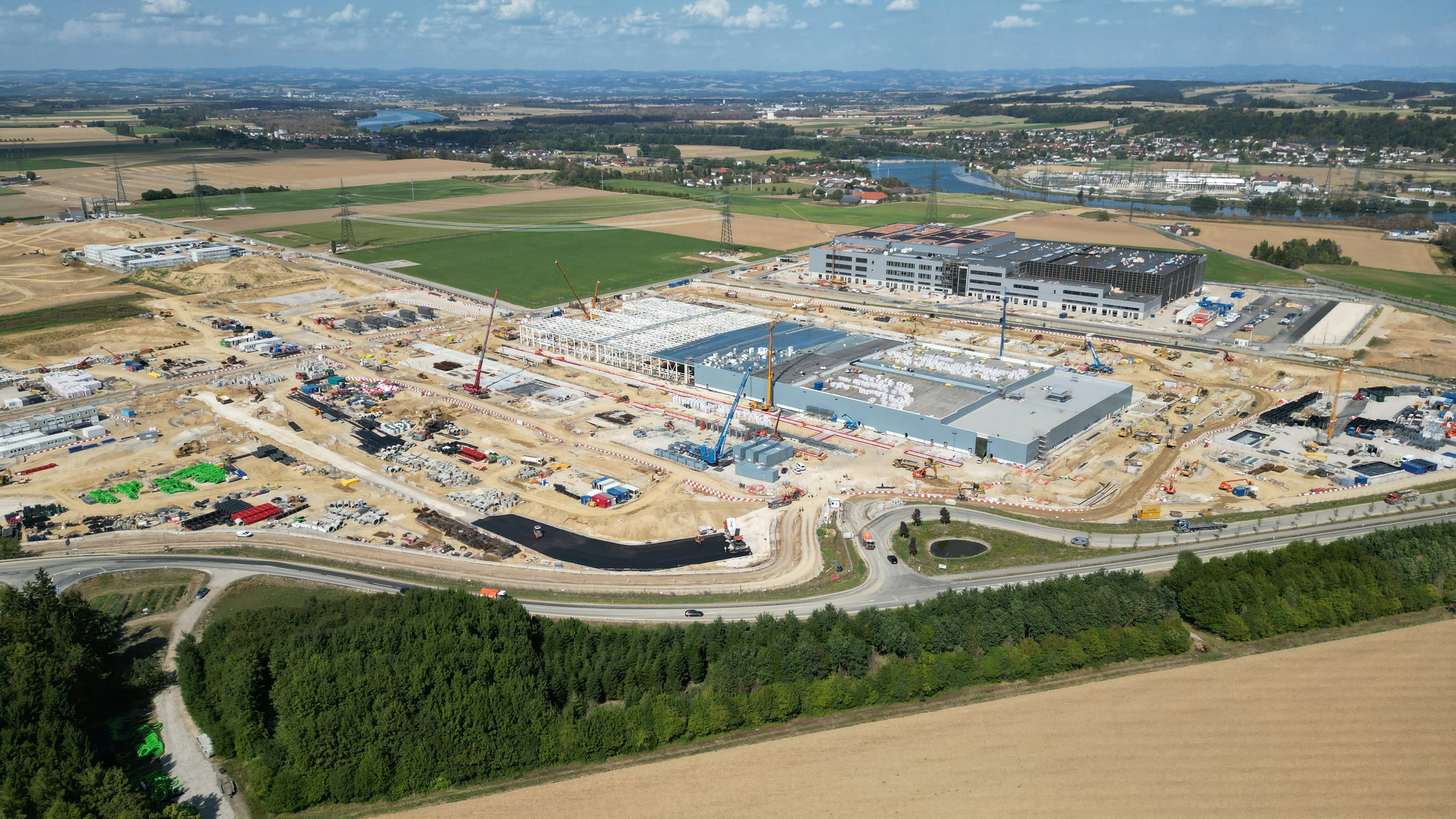 Aerial view of a large industrial construction site with cranes and unfinished buildings