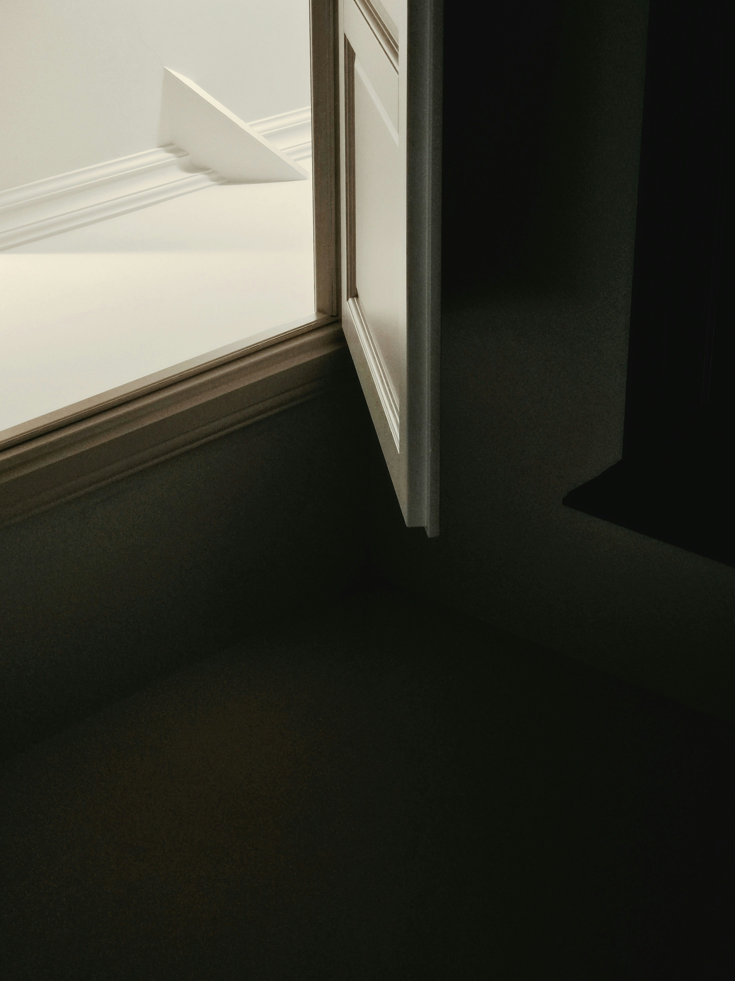 A partially open window with a wooden frame in a dark room
