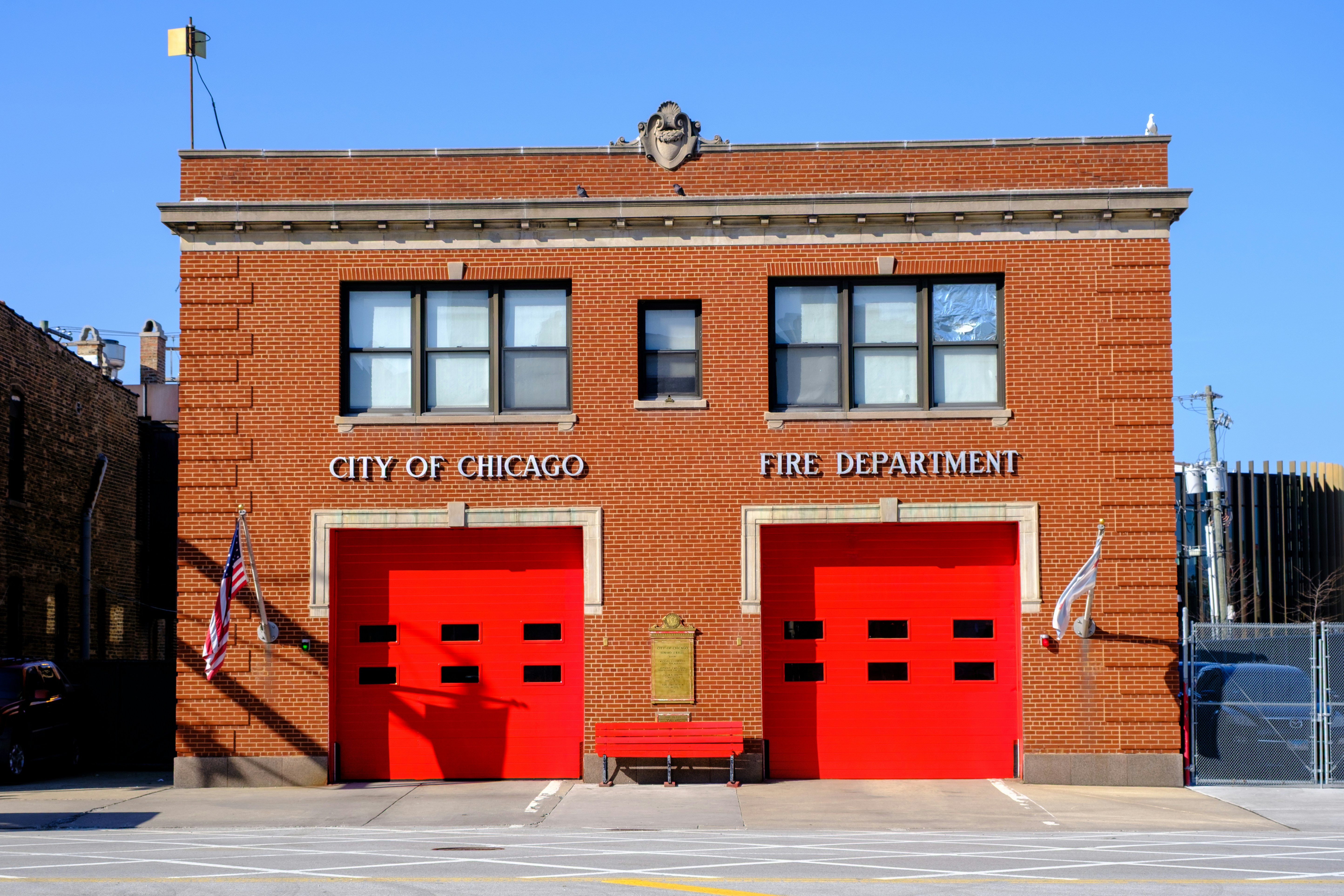 A red brick Chicago fire station with two bright red garage doors