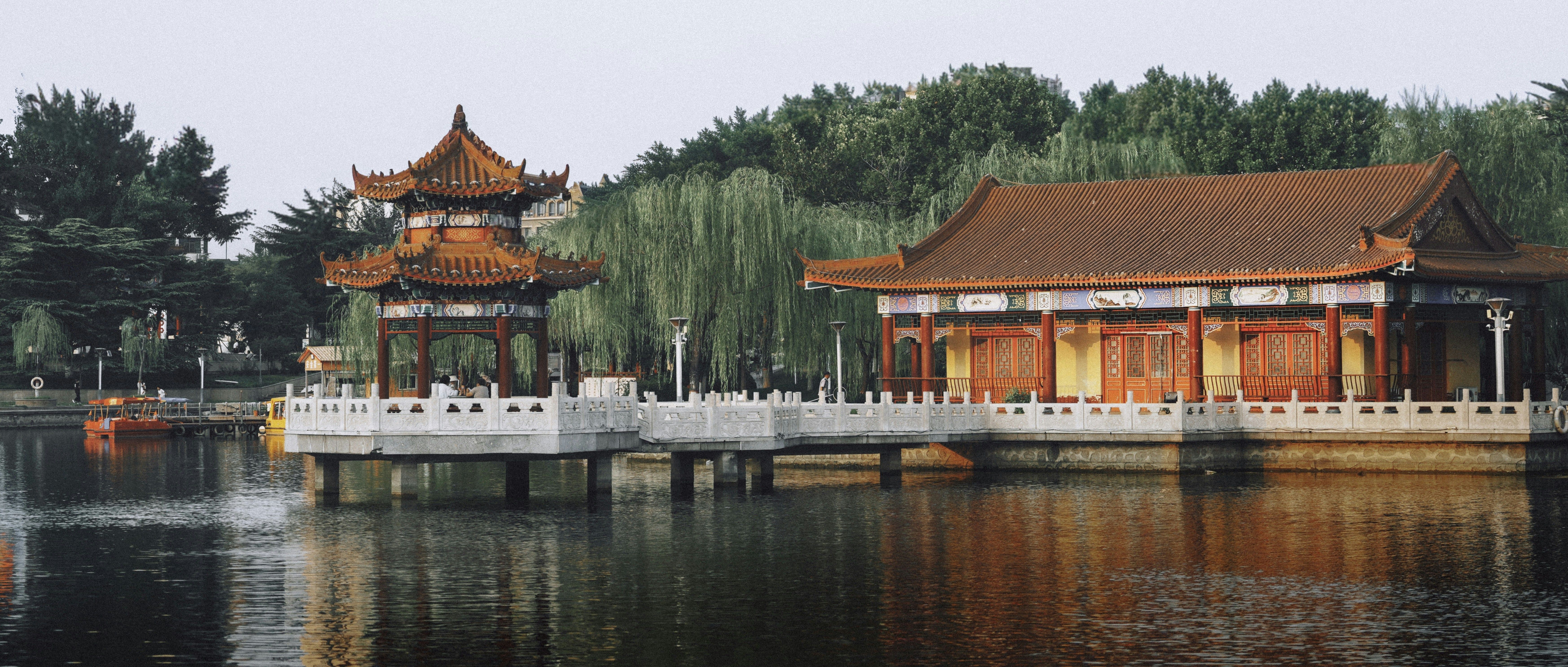 Traditional Chinese pavilion and building on a lake with weeping willow trees