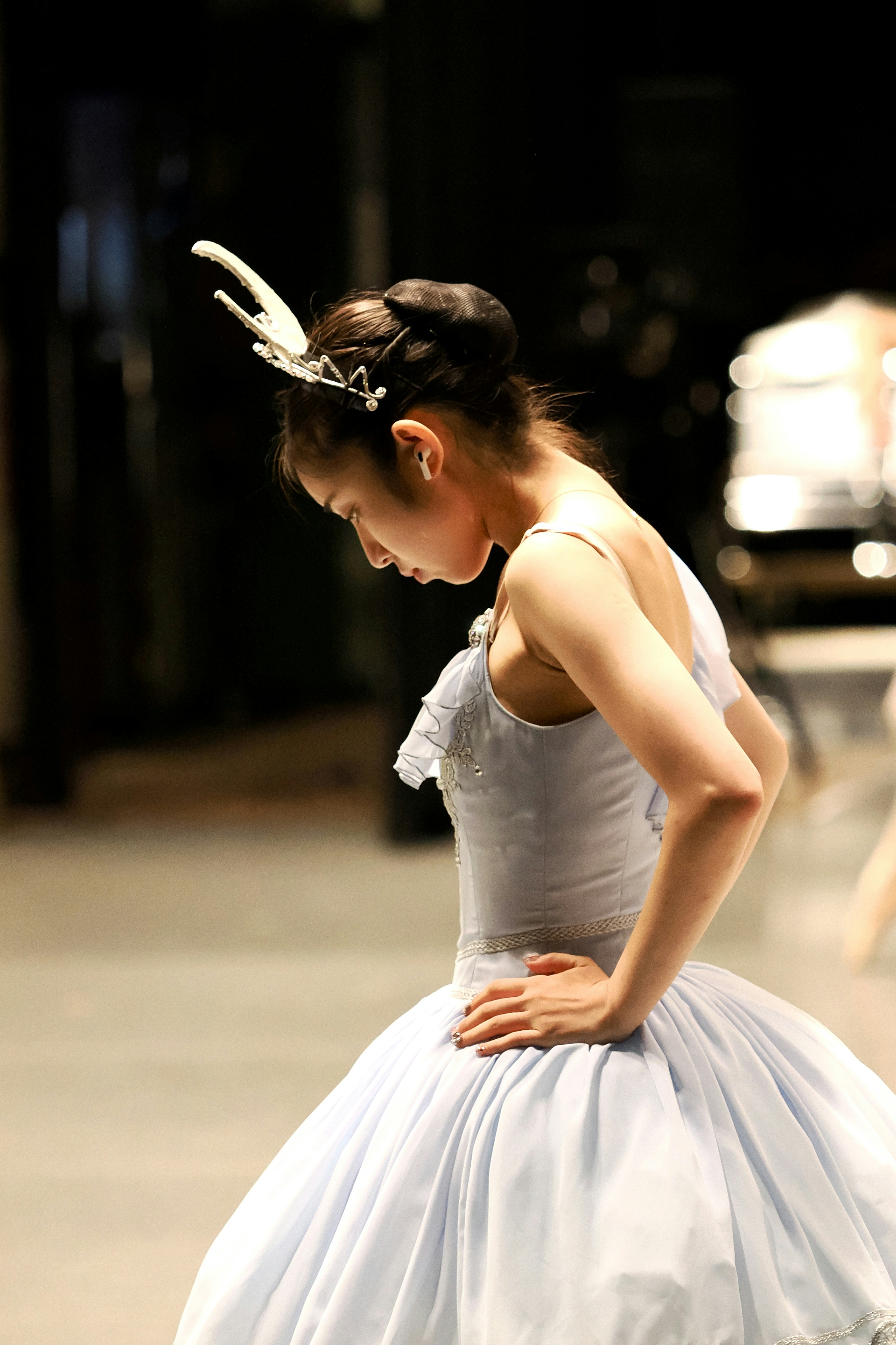 A ballerina in a light blue tutu with a white headpiece in a studio