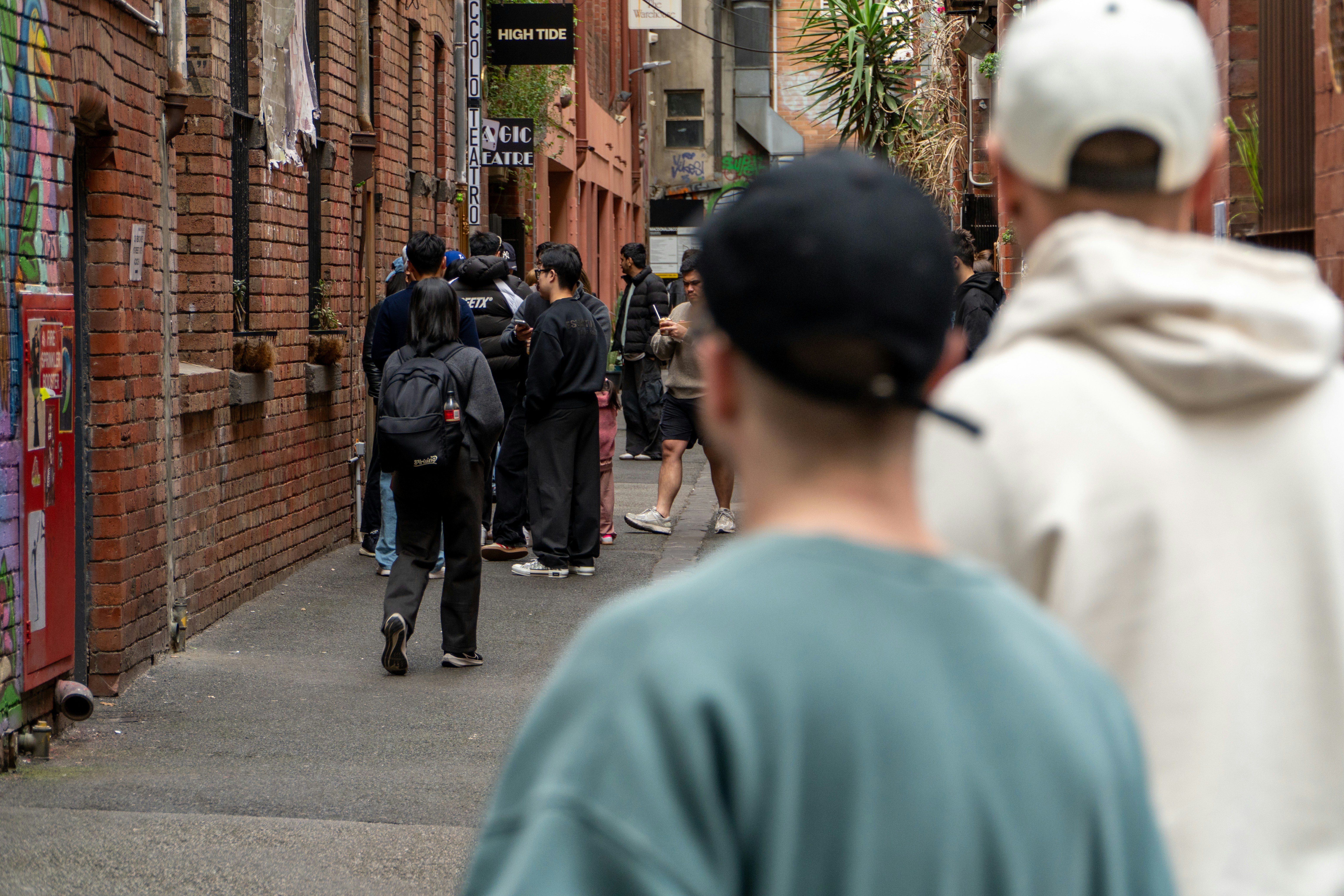 A group of people waiting in a narrow brick alleyway between buildings