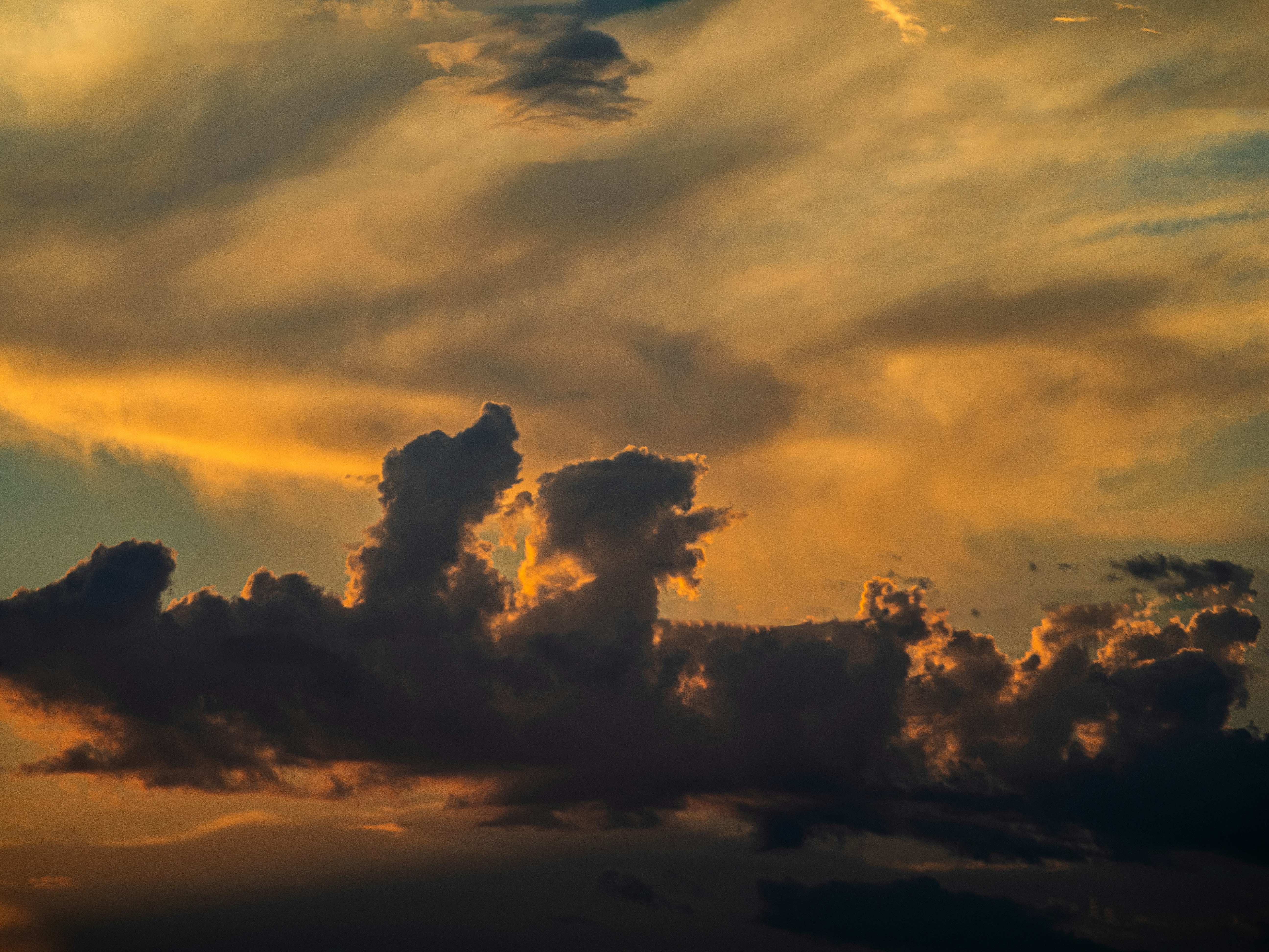 Dark clouds silhouetted against a bright orange and yellow sky