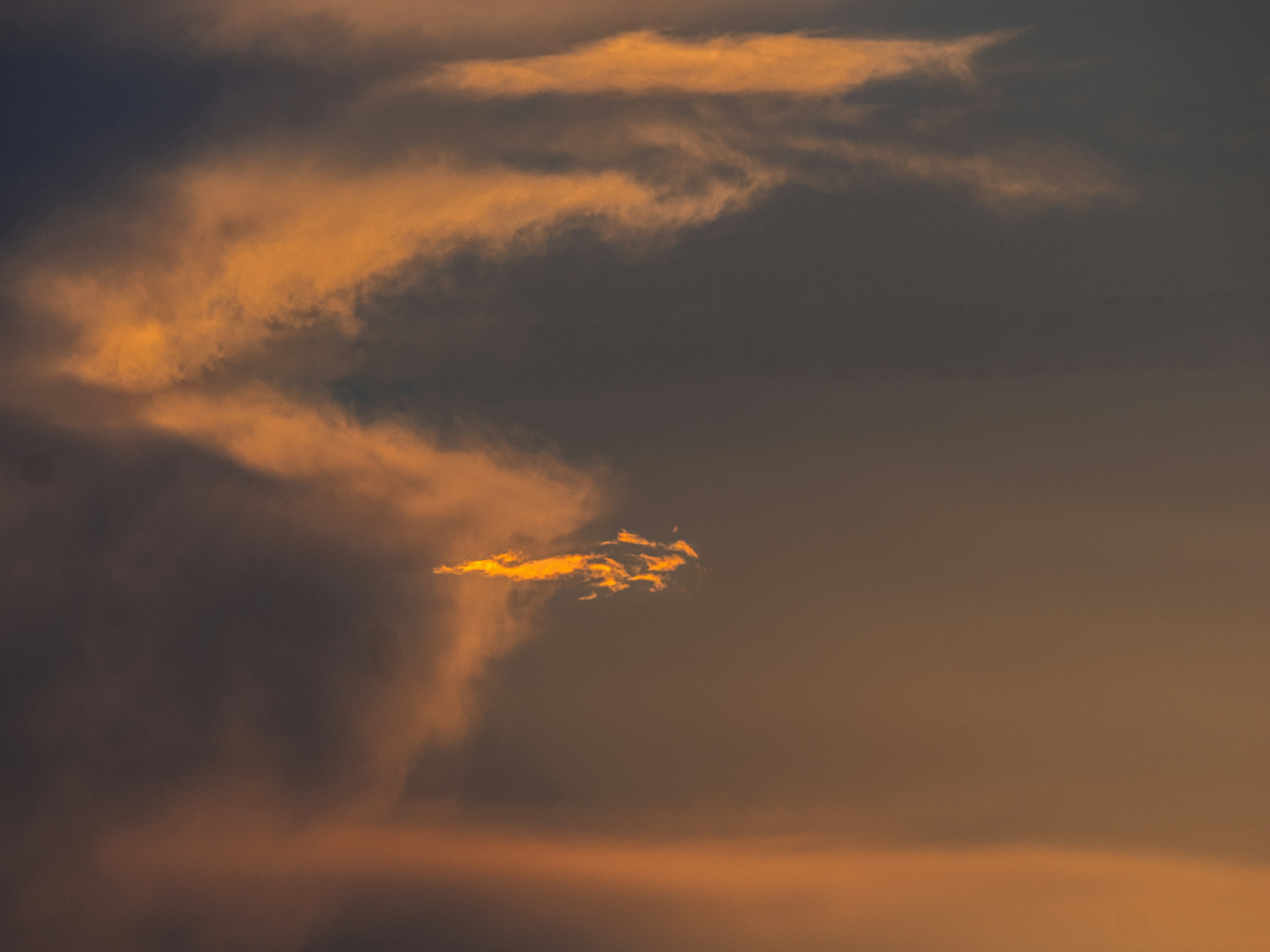 Dark grey clouds illuminated by warm golden light in the sky
