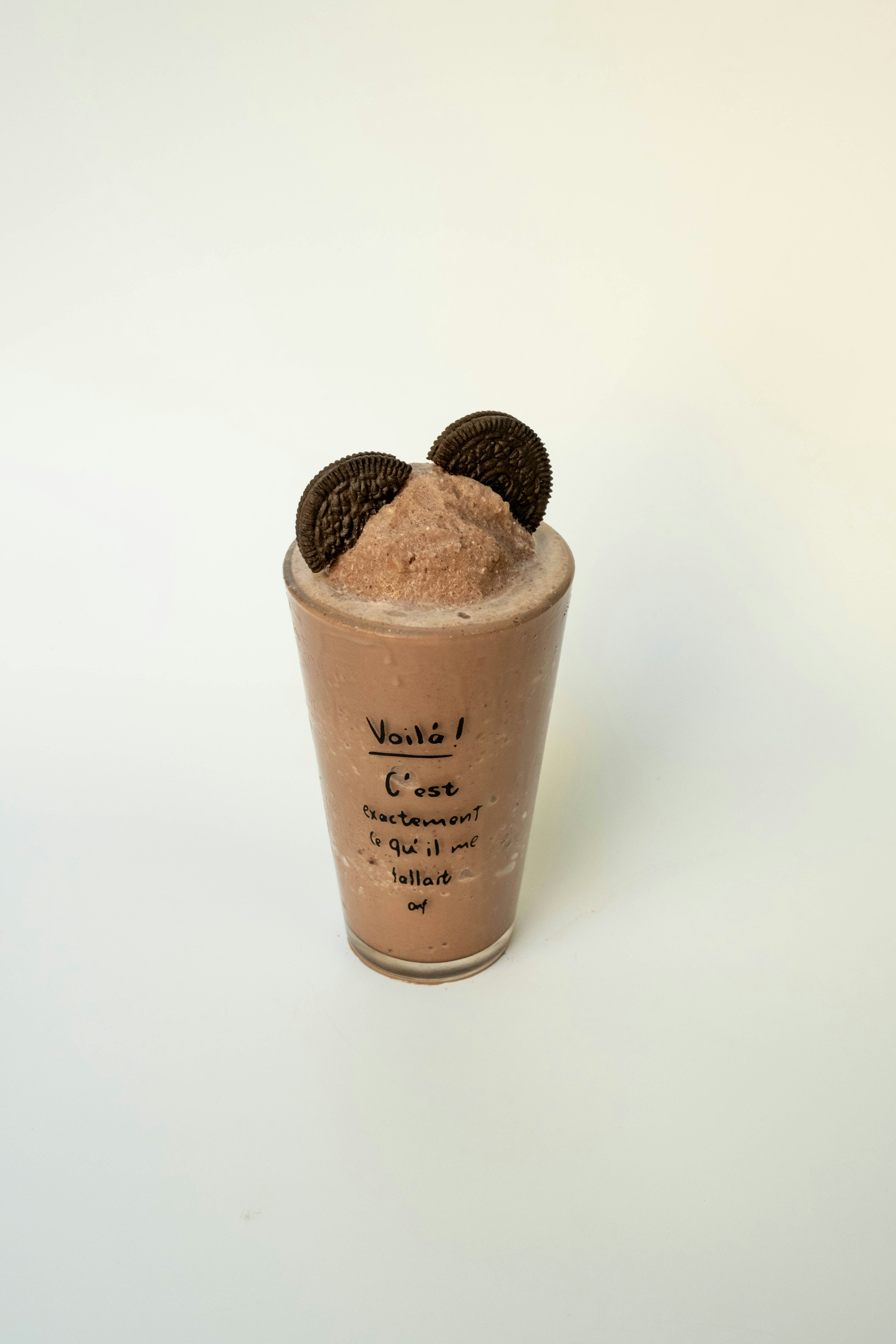 Um milkshake de chocolate coberto com dois biscoitos sanduíche em um copo sobre vinho branco