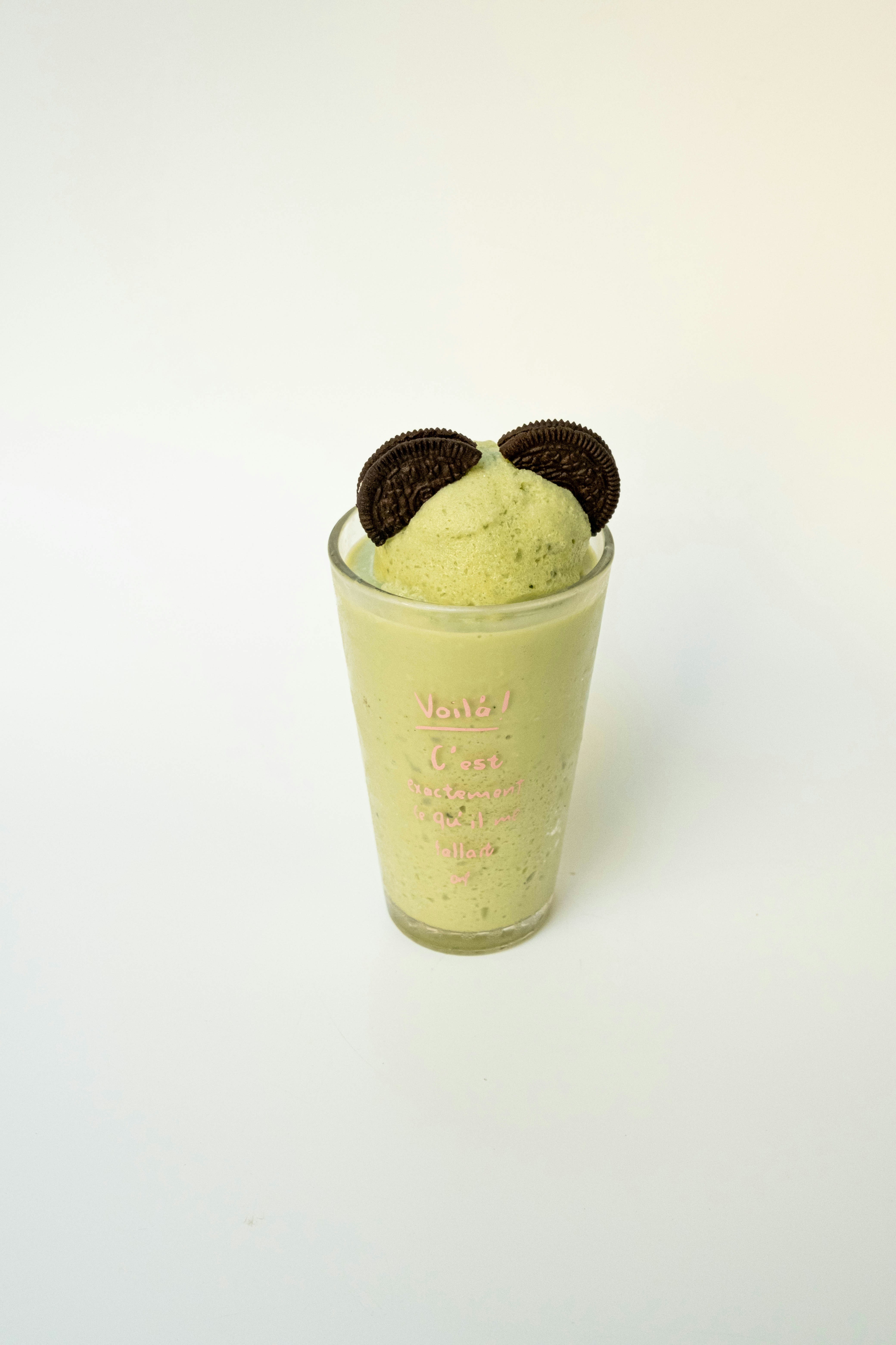 Um smoothie de matcha verde coberto com dois biscoitos de sanduíche de chocolate em um copo