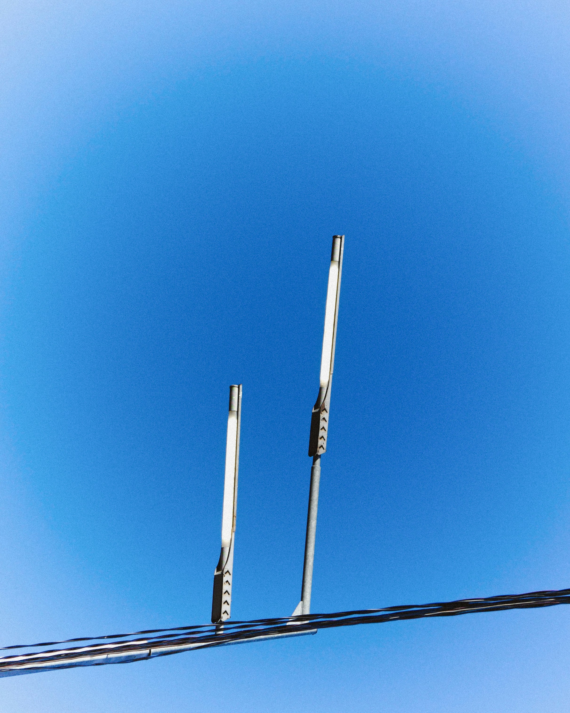 Due lampioni moderni contro un cielo azzurro limpido con linee elettriche