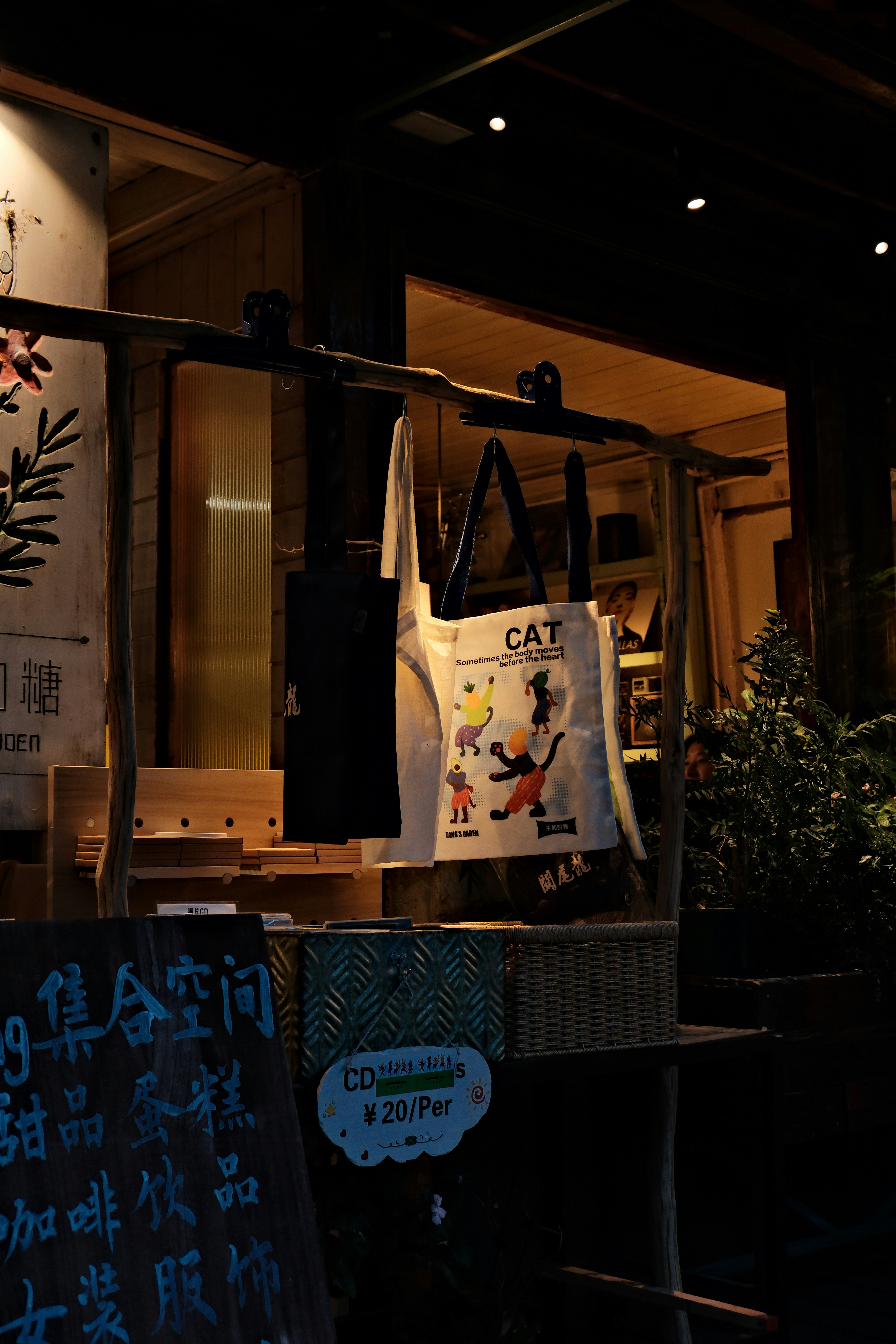 夜の店の外の木製ラックに吊るされたトートバッグ