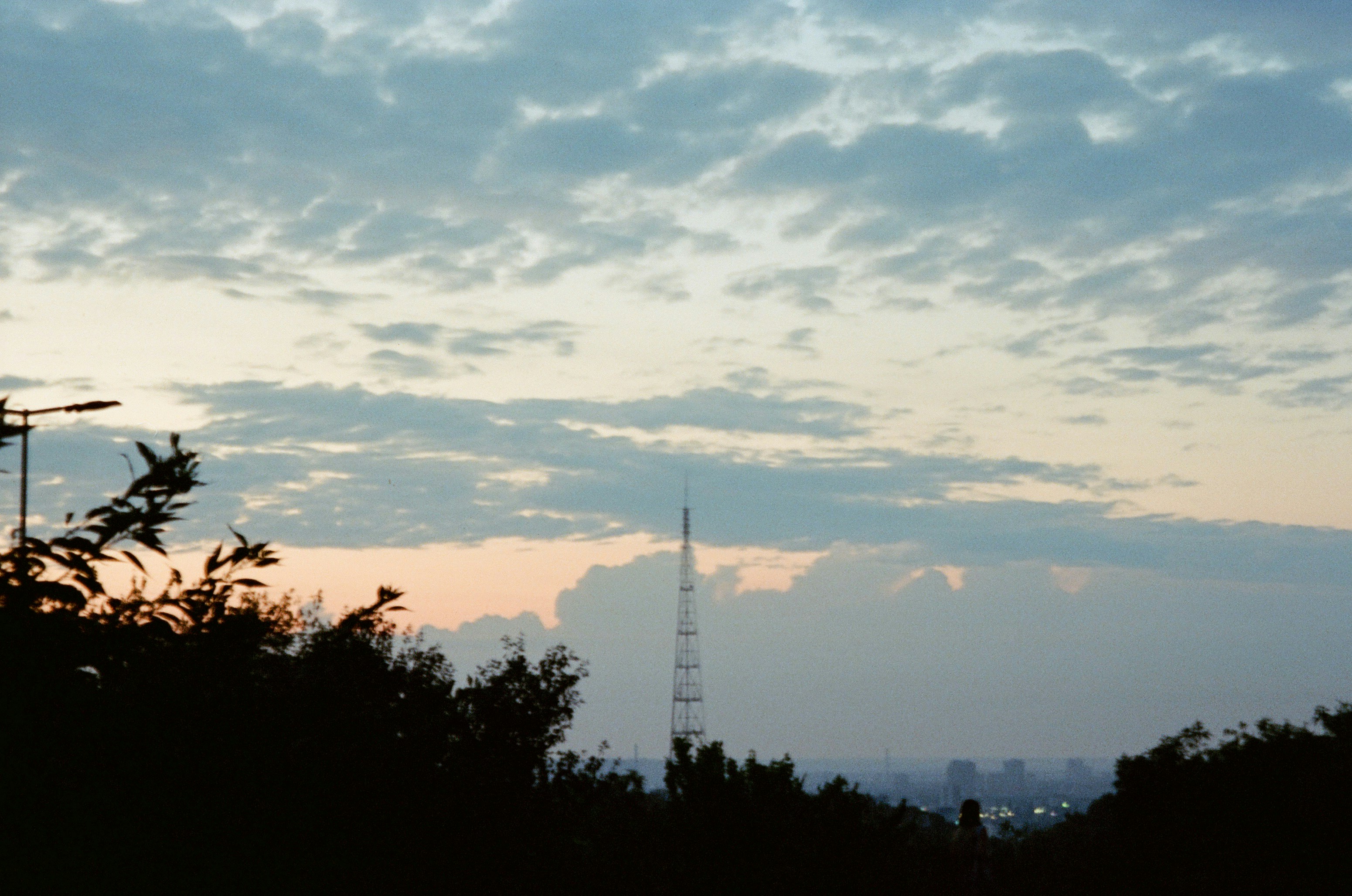 Una torre di comunicazione alta contro un cielo nuvoloso con una luce calda all'orizzonte