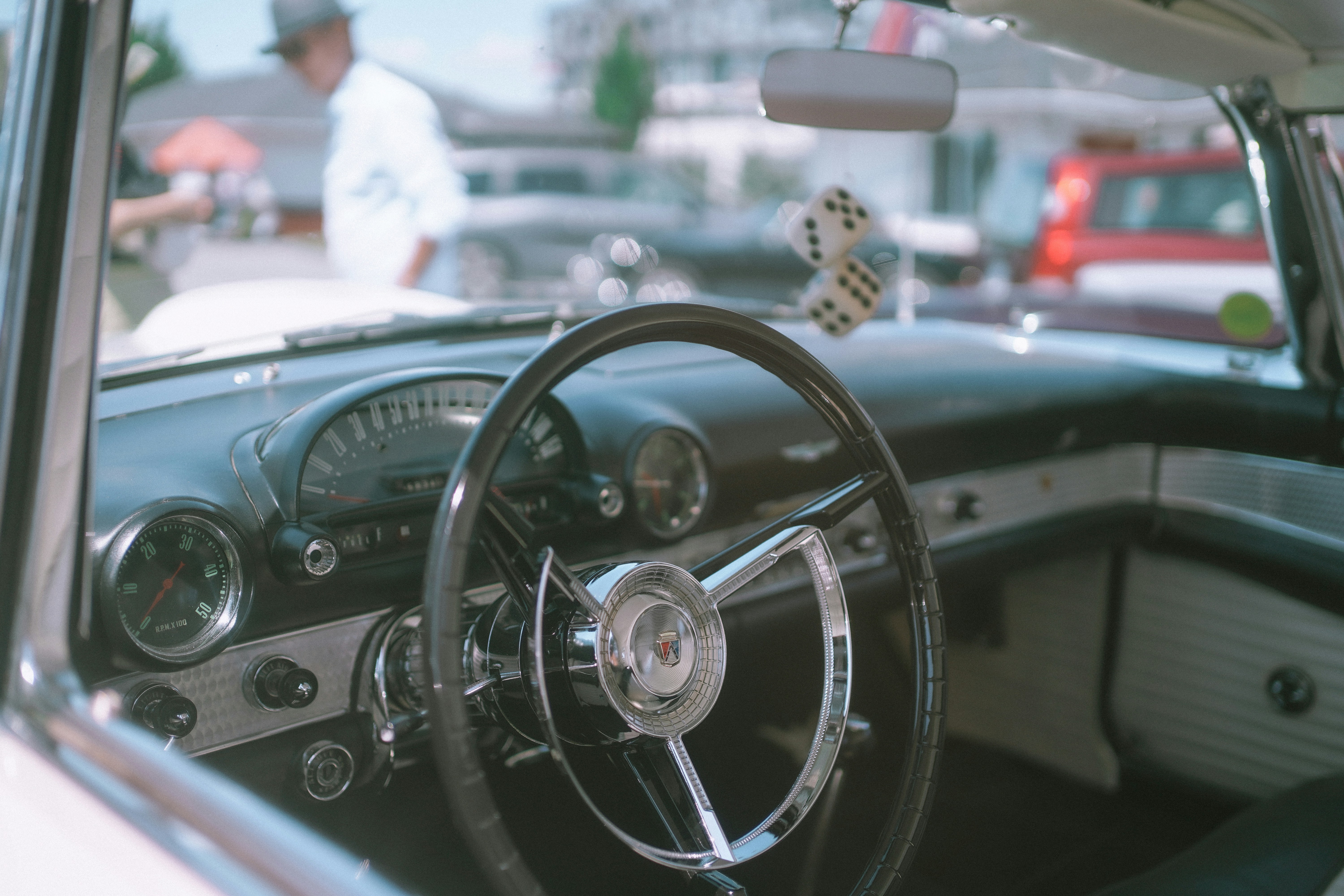 The interior of a vintage car with a steering wheel and fuzzy dice