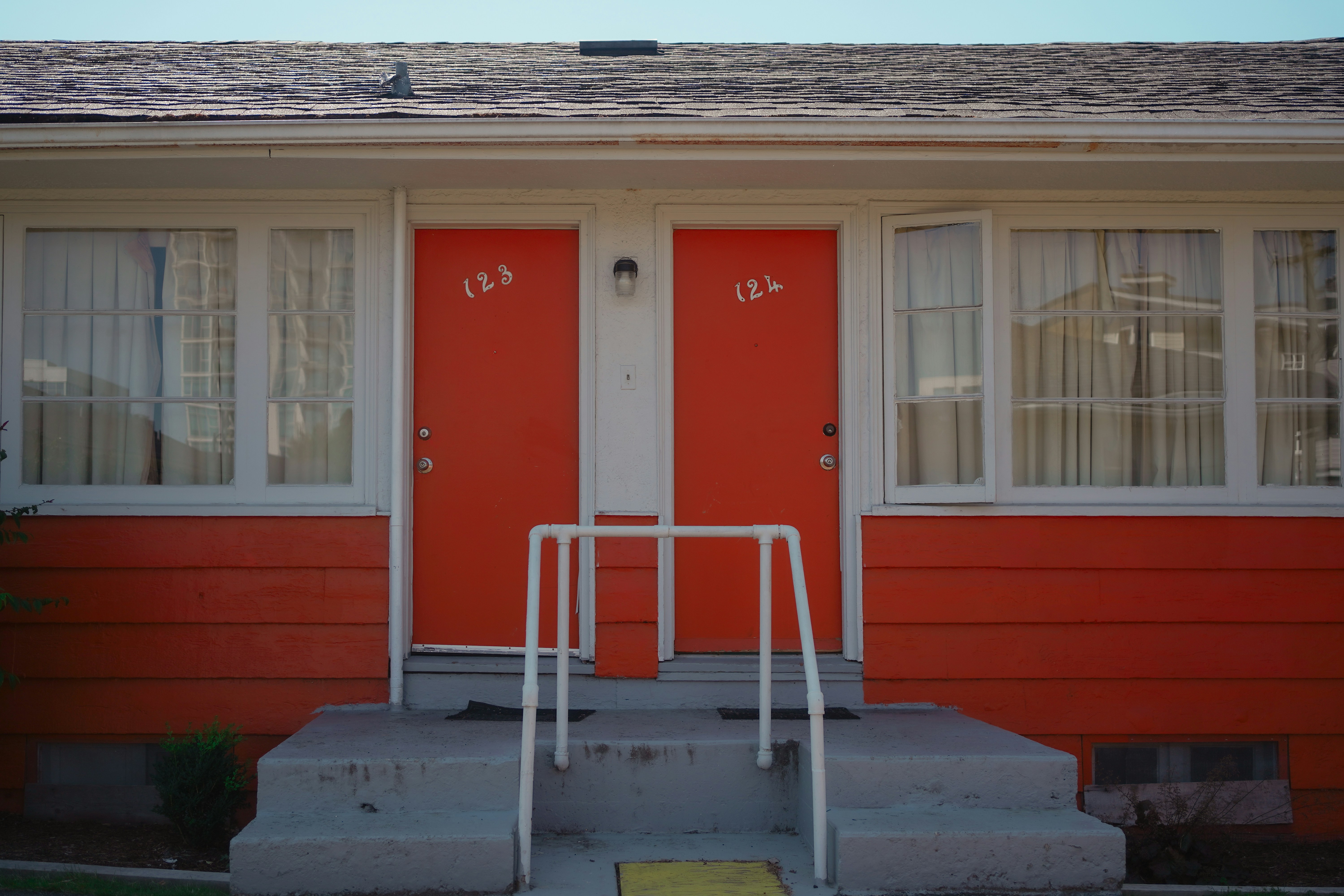 Two bright orange doors with numbers 123 and 124 on a building exterior