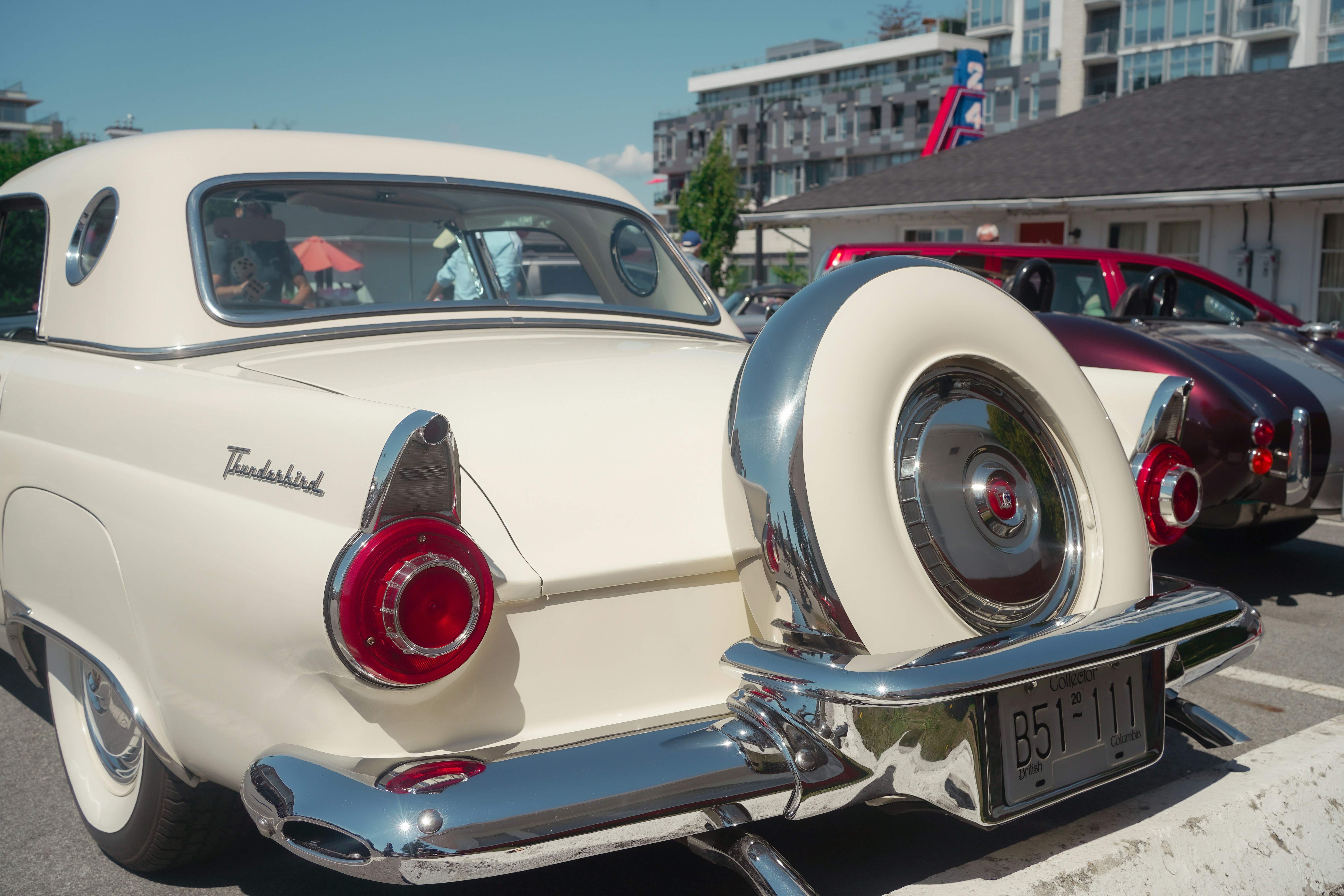 Rear view of a white vintage Ford Thunderbird with a chrome spare tire cover