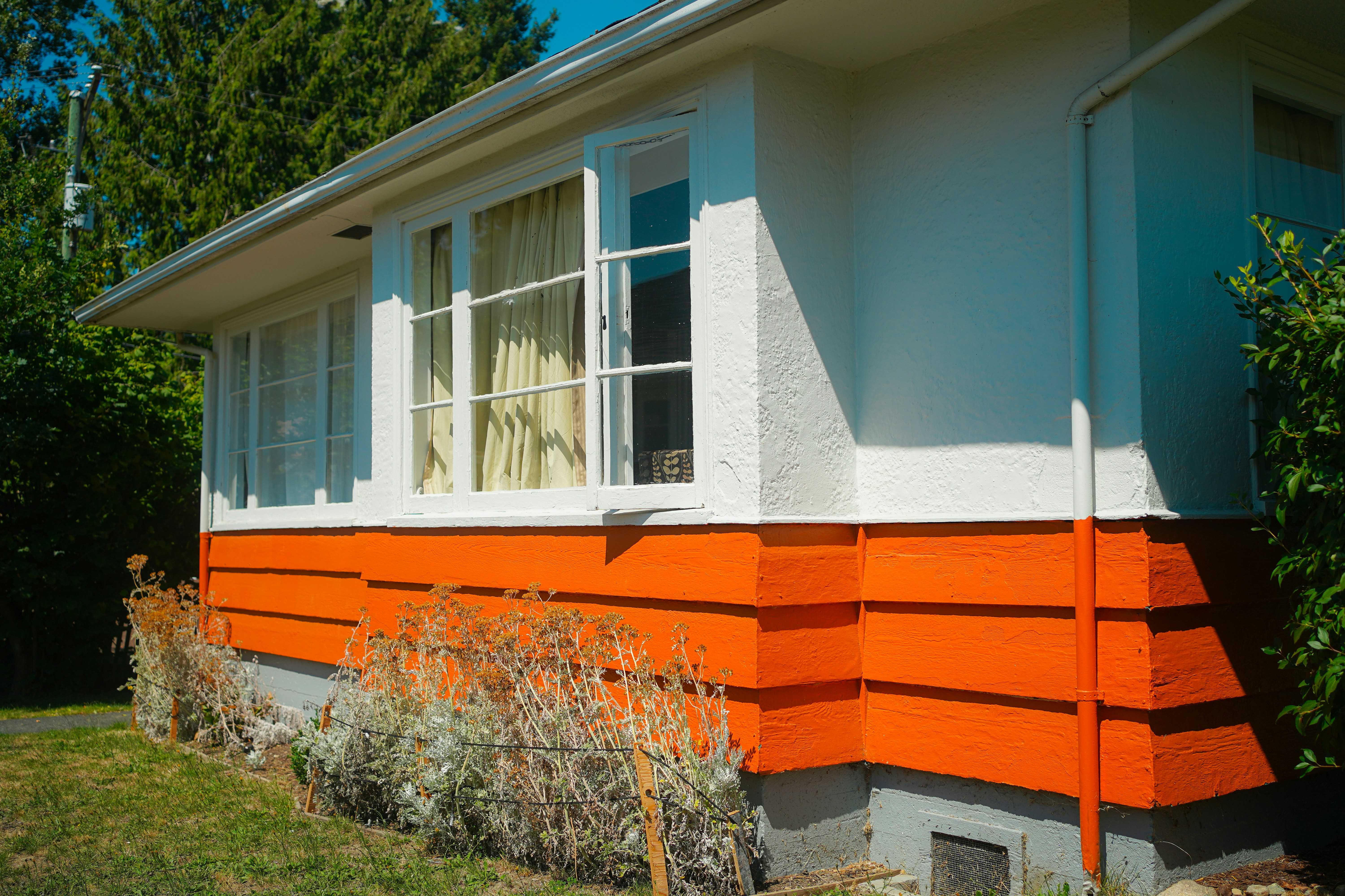 A house exterior with white walls and bright orange horizontal siding