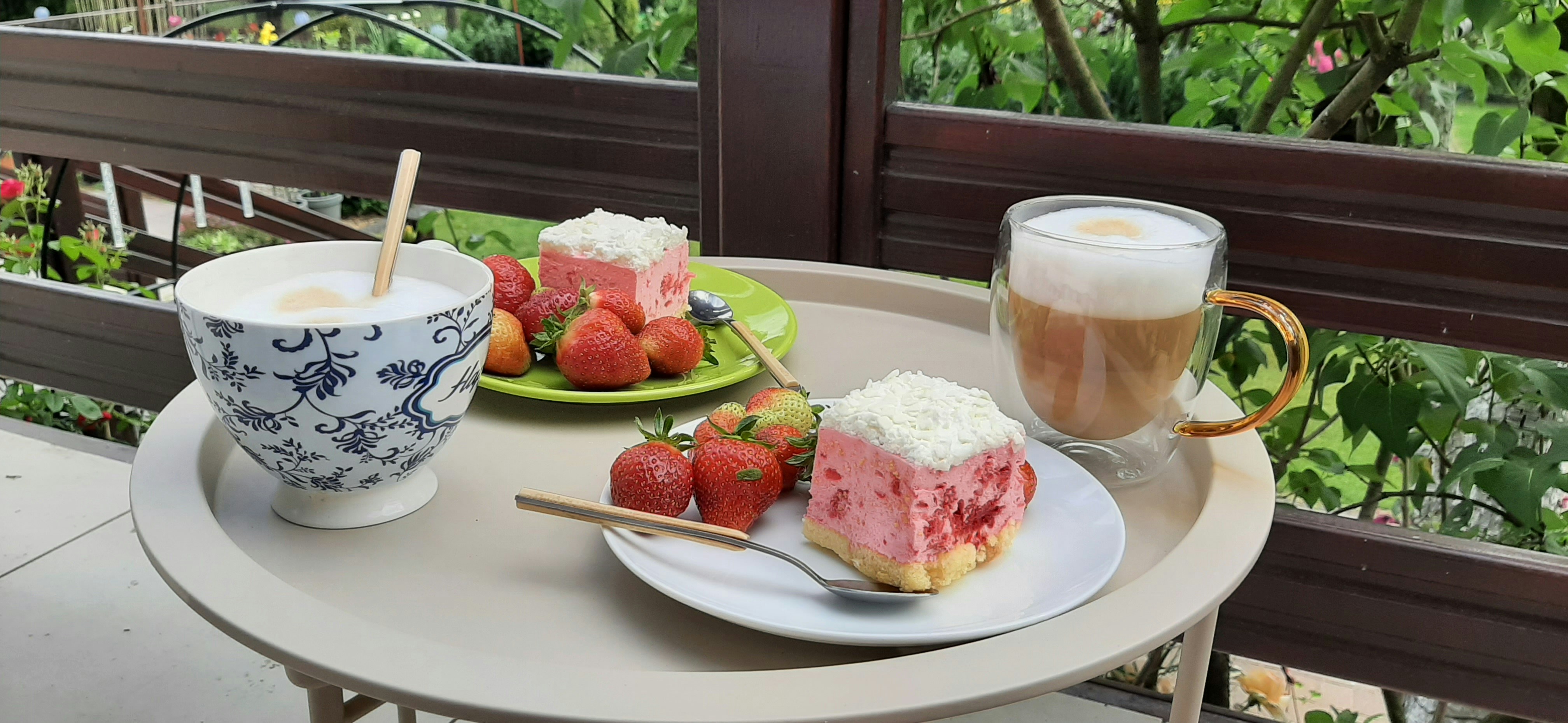 Two plates with strawberry cake and fresh strawberries beside two cups of coffee