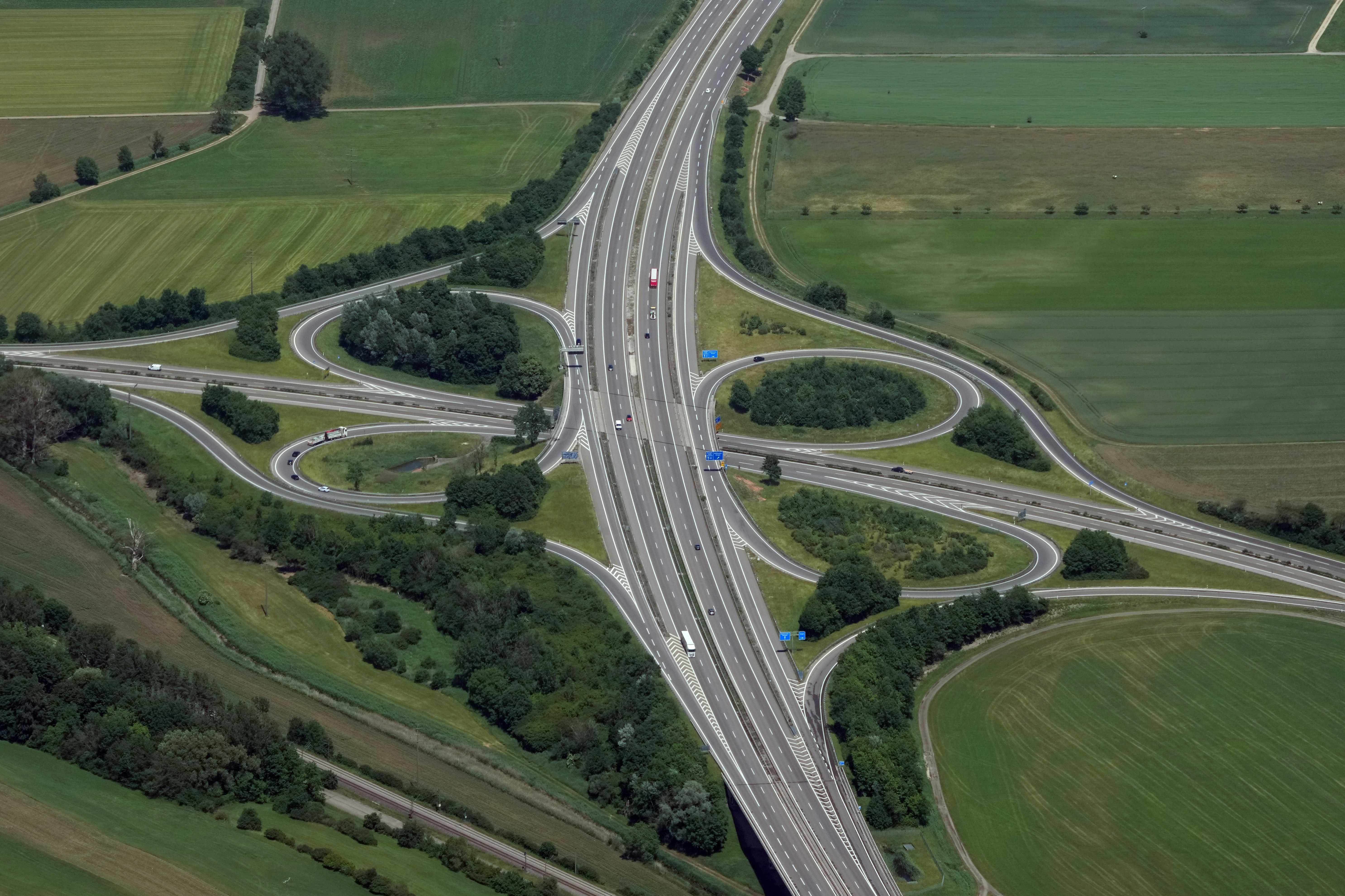 An aerial view of a highway interchange surrounded by green agricultural fields