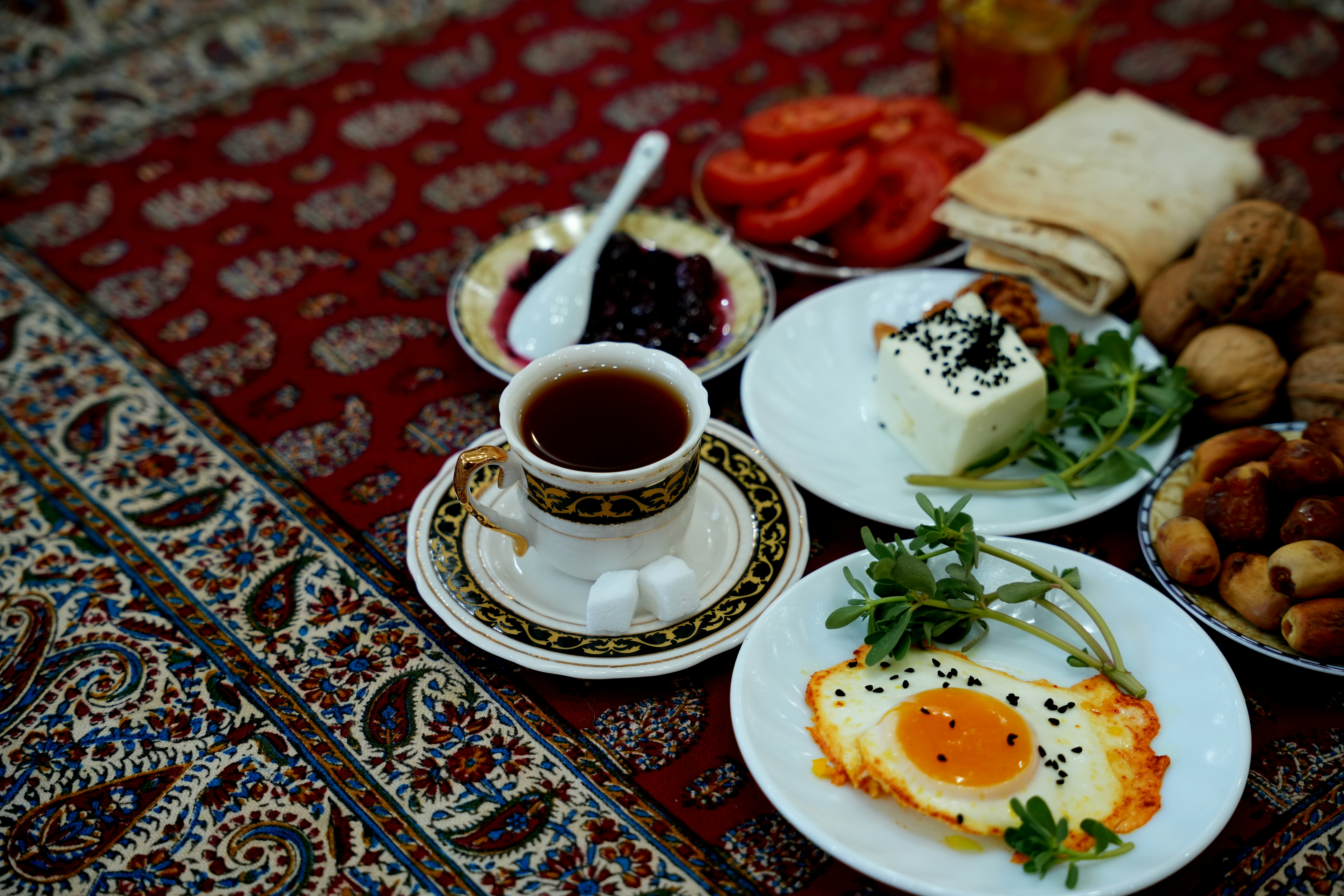 A crowded Turkish kahvaltı table with white cheese, olives, tomatoes, honey, jams, menemen, bread, and tulip glasses of tea
