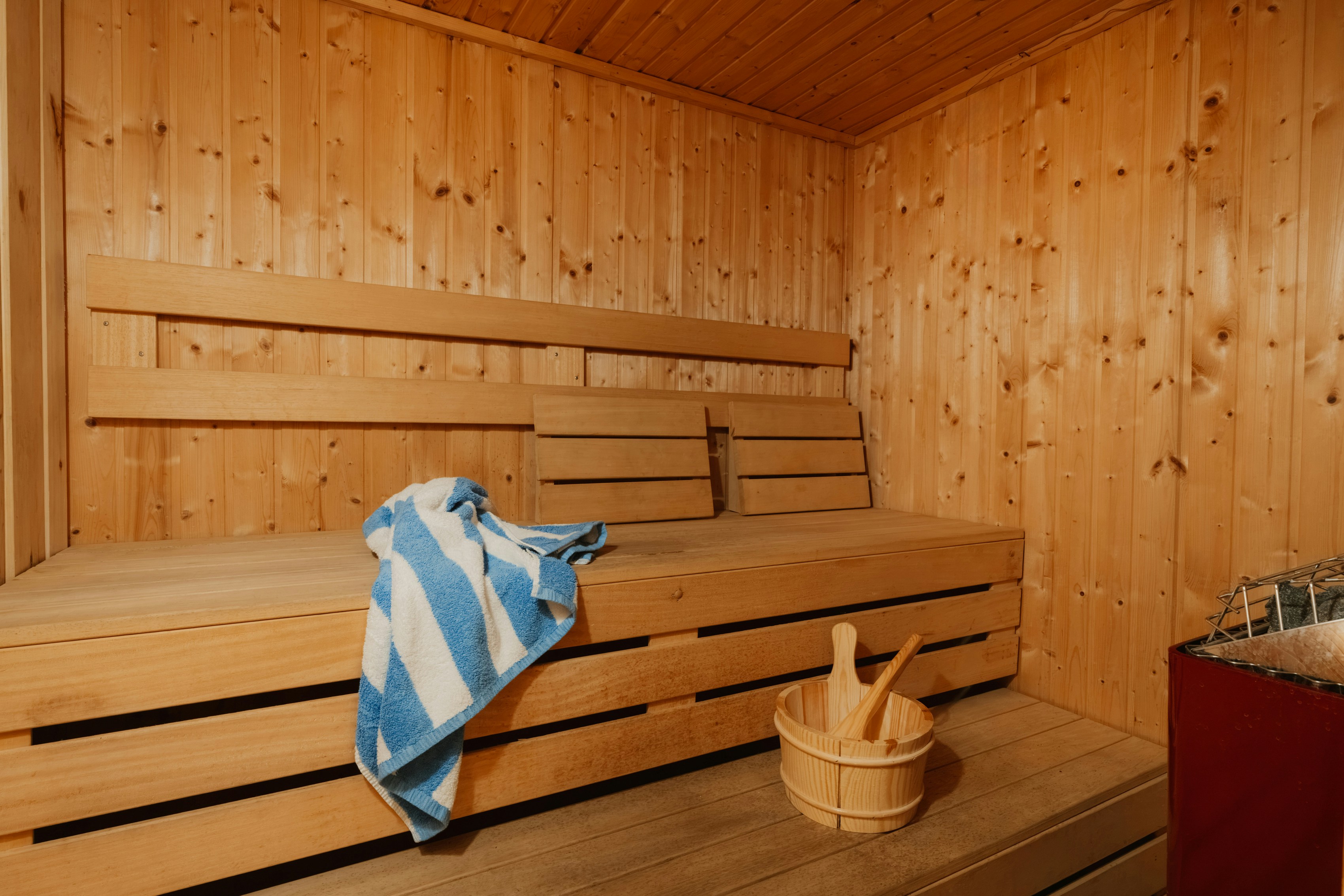 A blue and white striped towel on a wooden sauna bench with a bucket