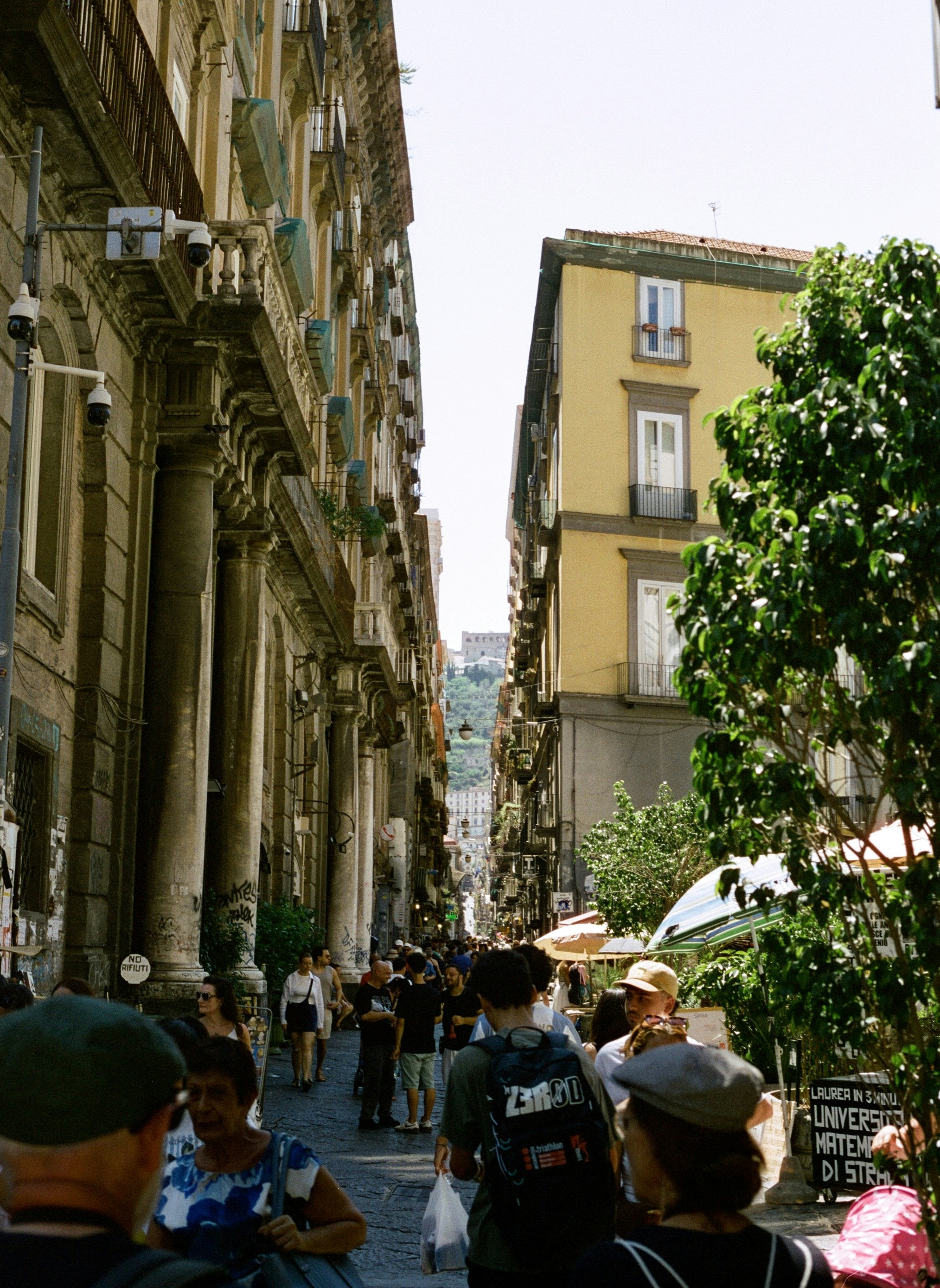 A crowd of people walking down a narrow street between tall historic buildings