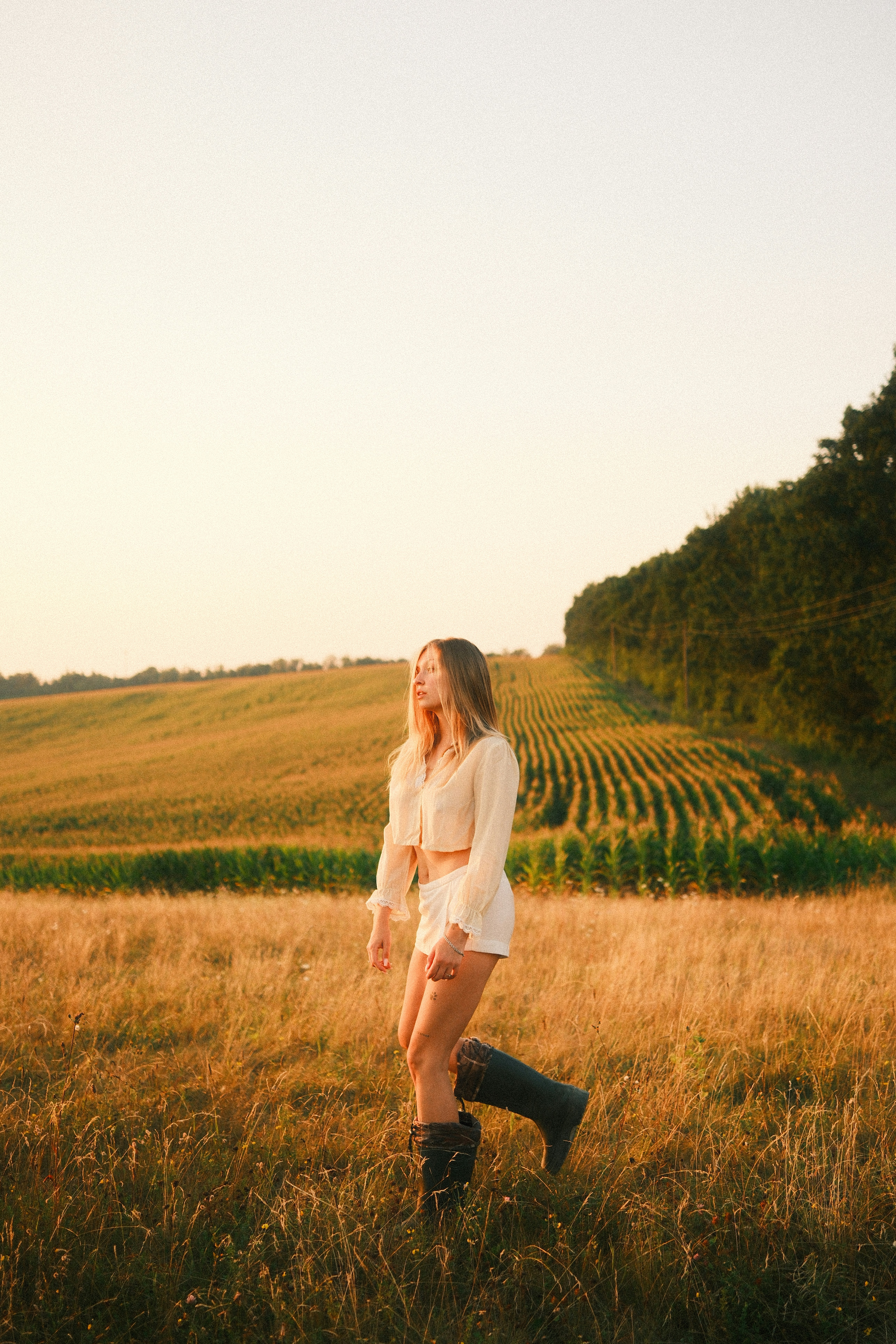A woman in a light top and shorts walking through a golden field
