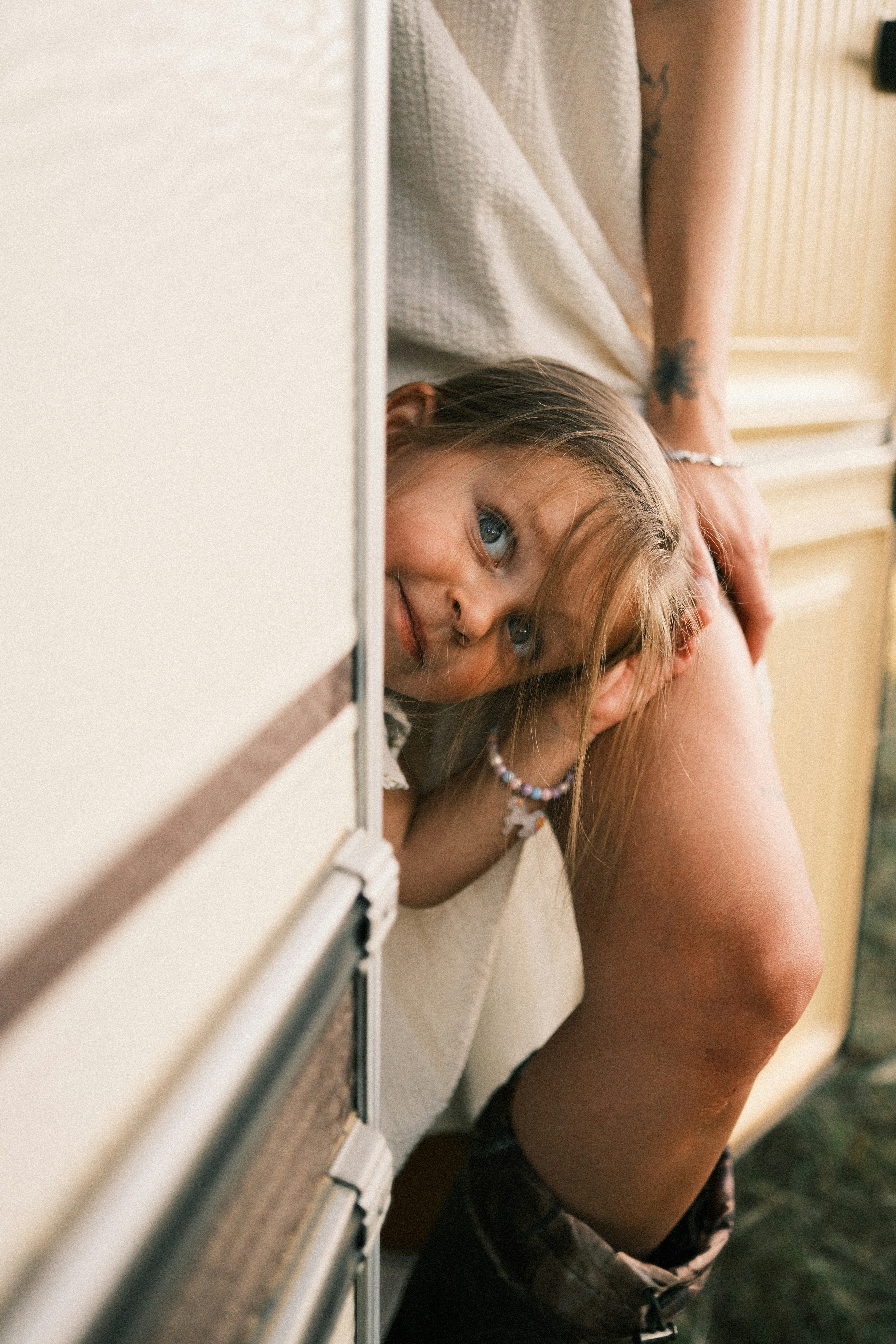 A child peeking from a camper doorway beside an adult's leg