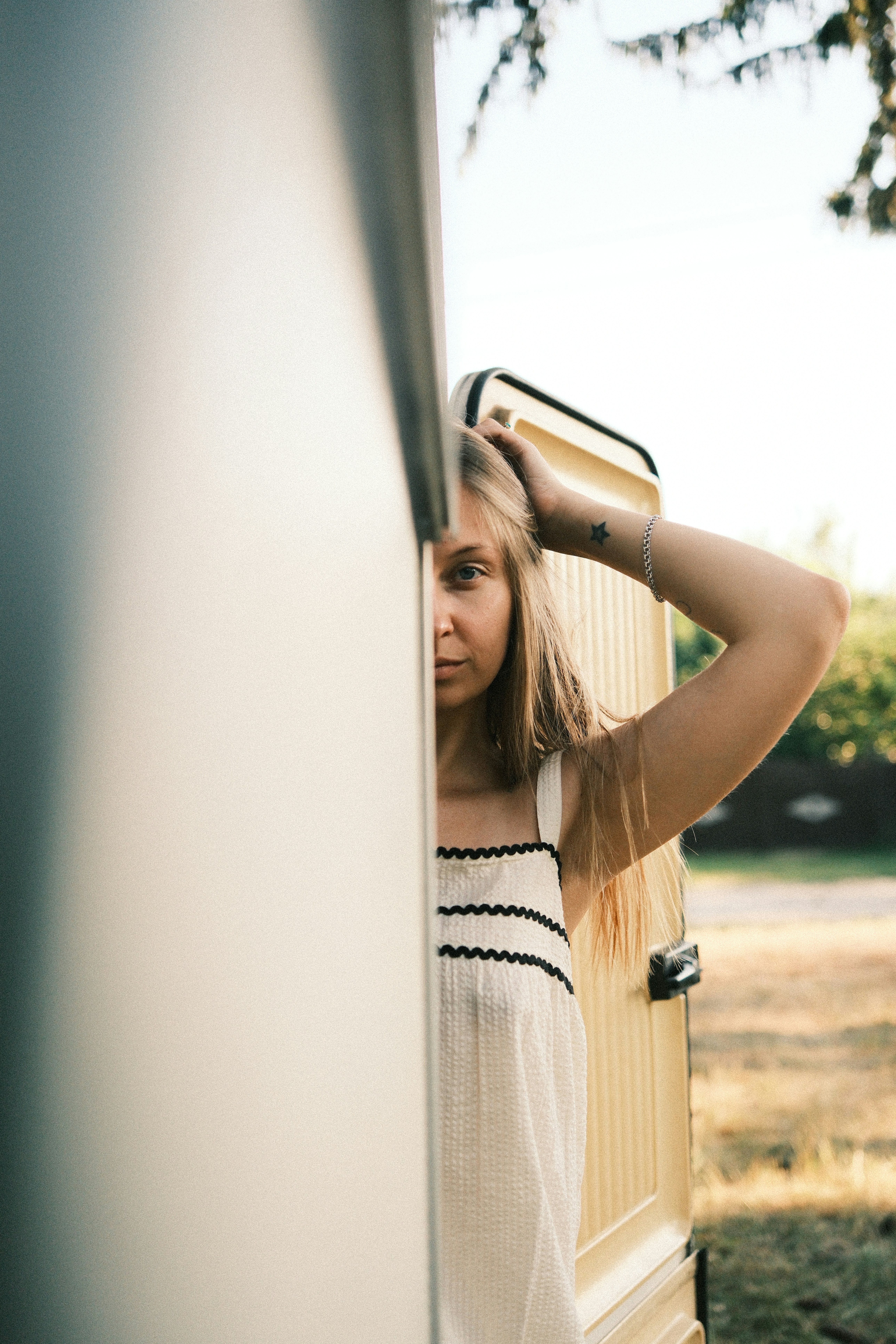 A woman with a star tattoo on her wrist peeking from behind a door