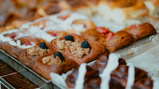 Fresh danish pastries topped with blackberries and crumble on a metal baking tray