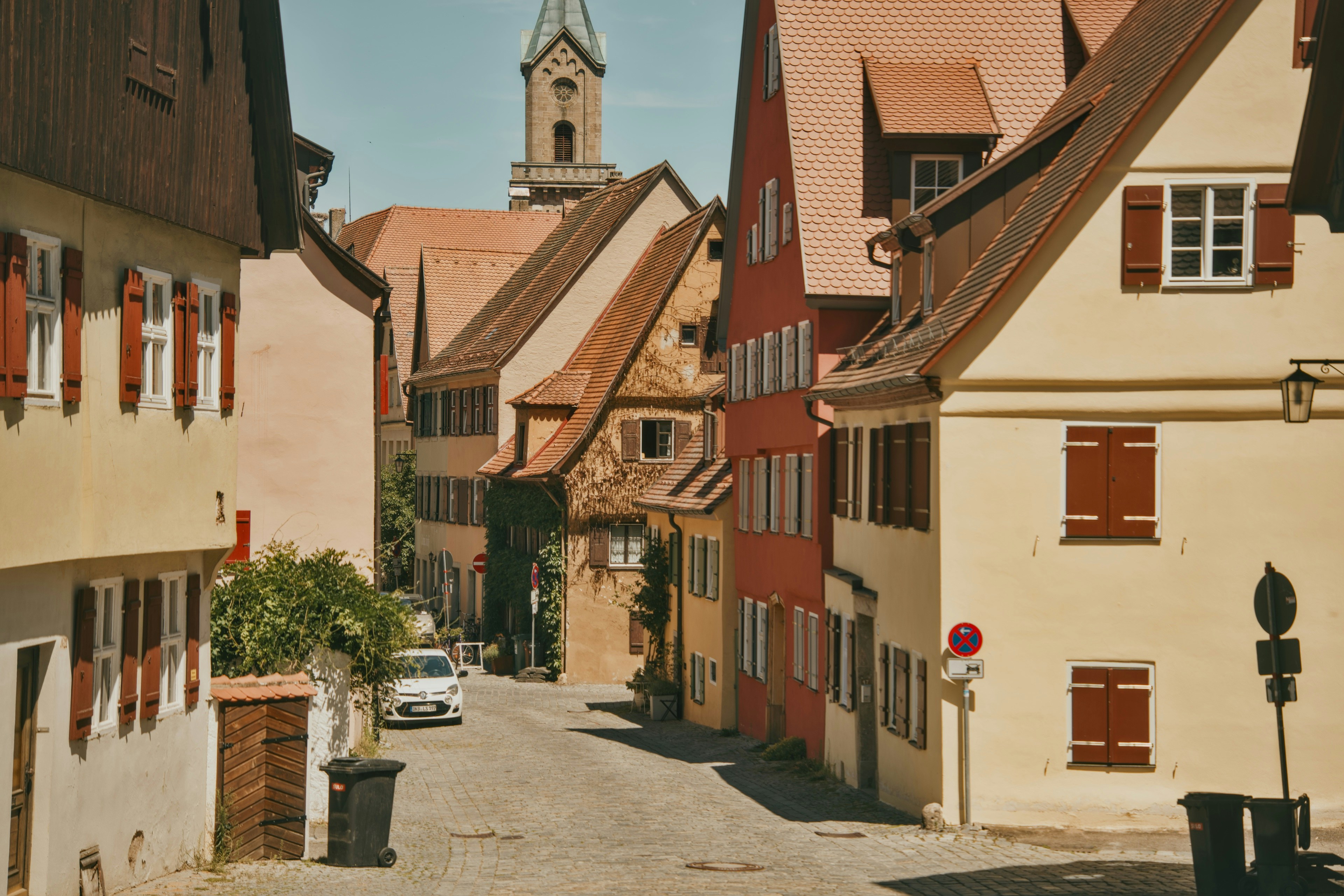 Una stretta strada in ciottoli fiancheggiata da colorate case storiche e una torre di chiesa