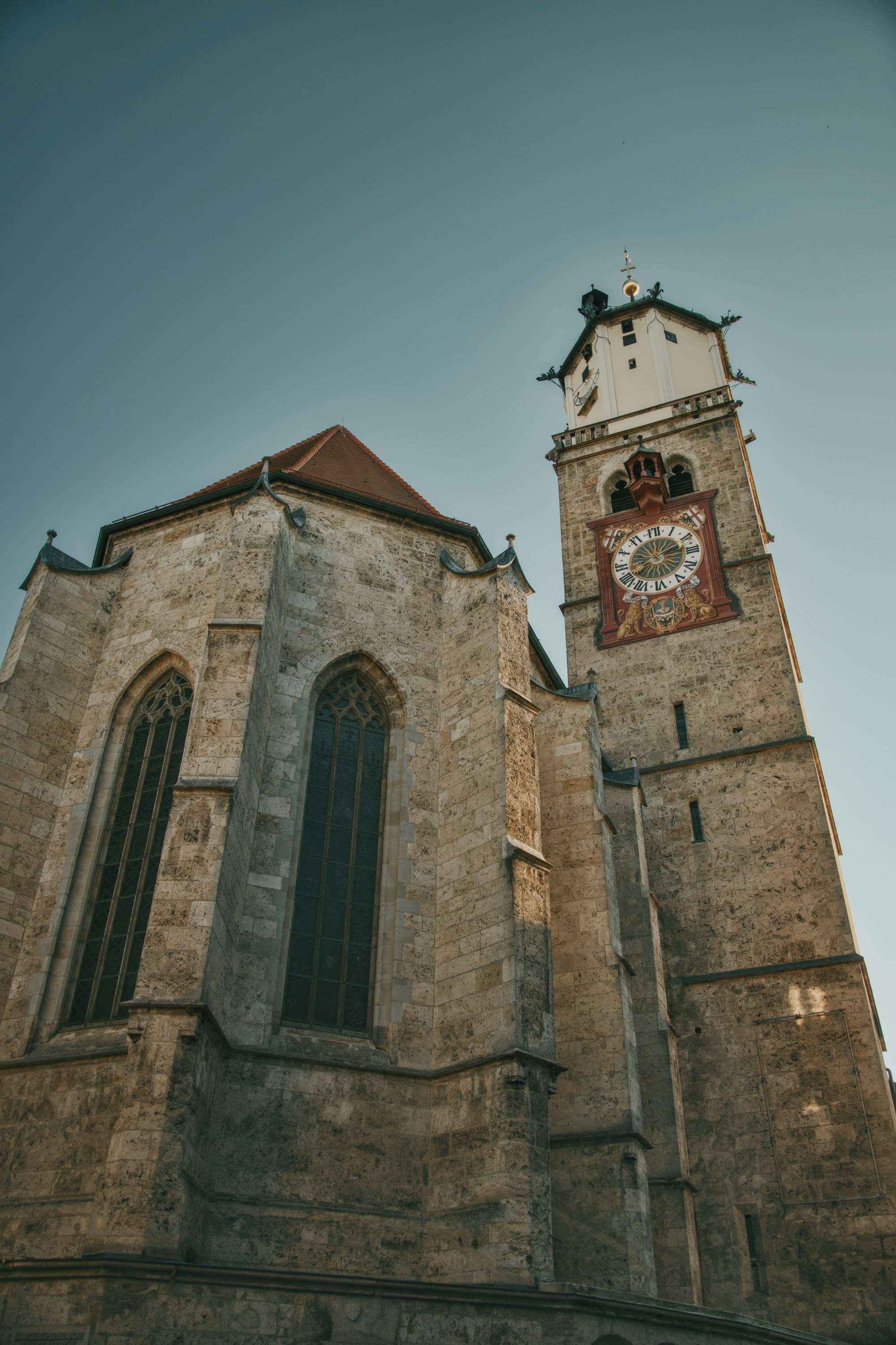Una chiesa in pietra con una torre dell'orologio alta contro un cielo azzurro limpido