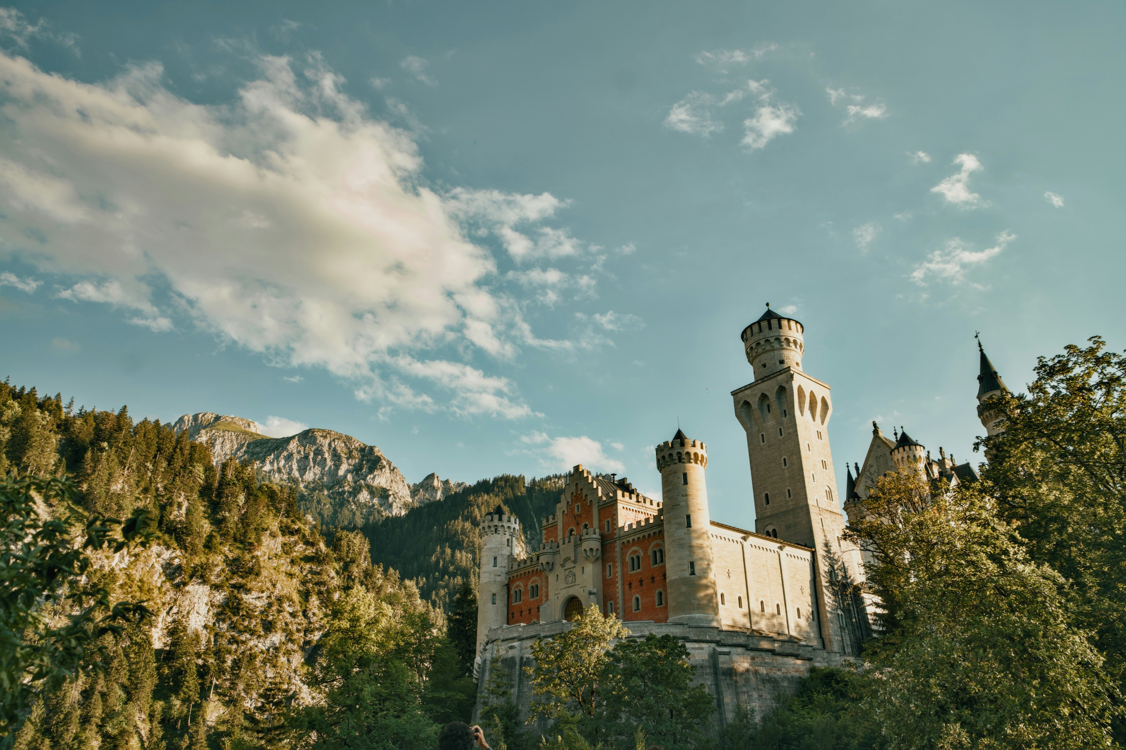 Il Castello di Neuschwanstein immerso nelle Alpi Bavaresi sotto un cielo azzurro brillante