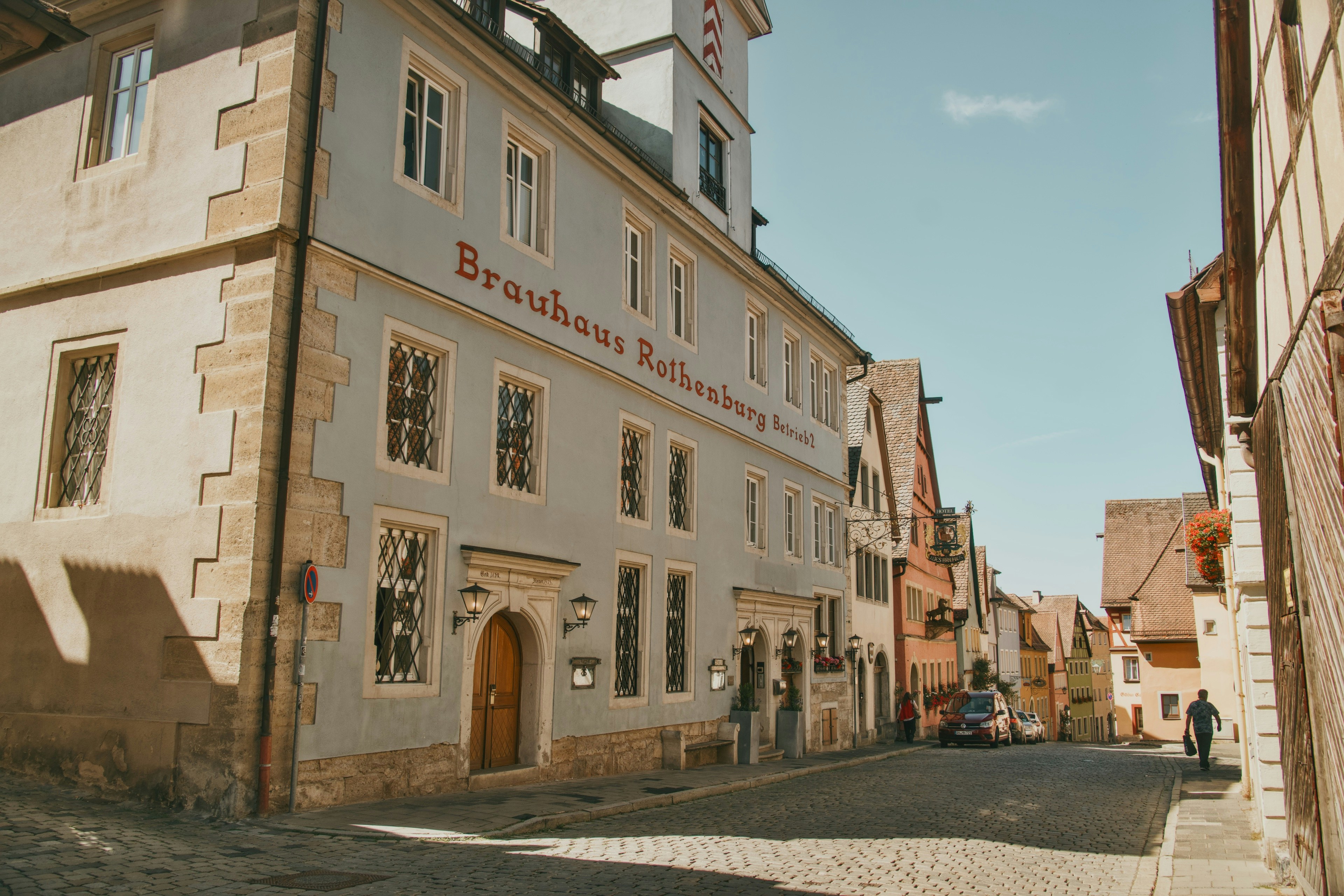 Una strada acciottolata a Rothenburg ob der Tauber con edifici storici e un birrificio