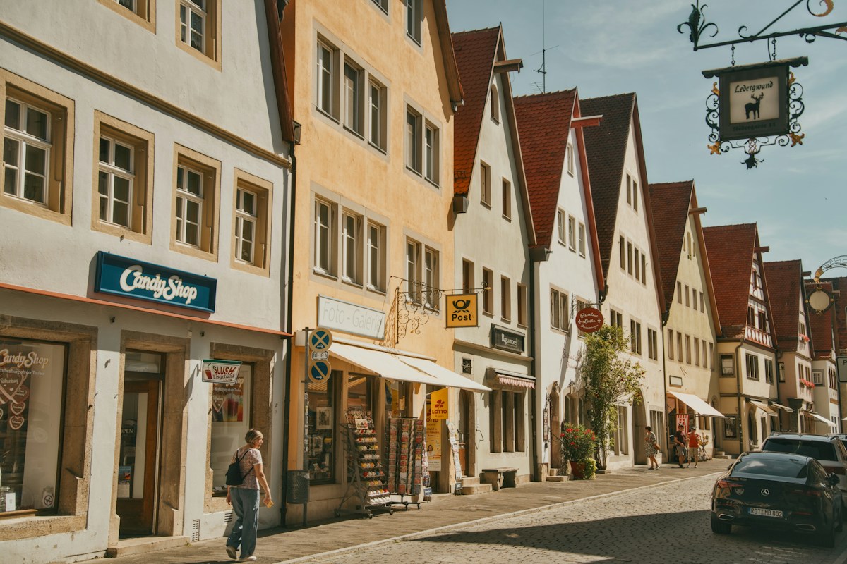 Un passant longe des maisons à colombages et des boutiques dans une rue pavée presque déserte