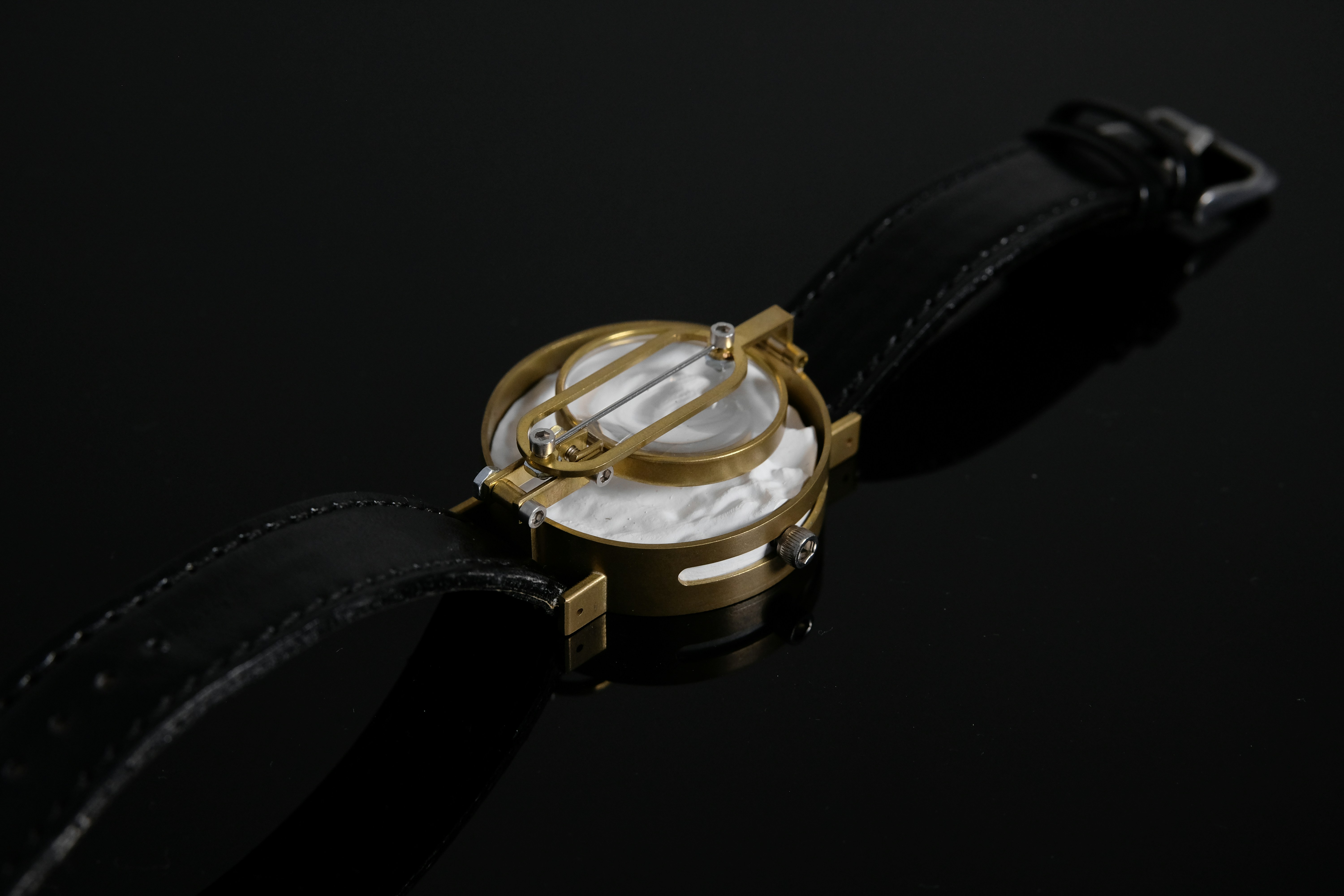 A dress watch with a textured white dial on a black leather strap