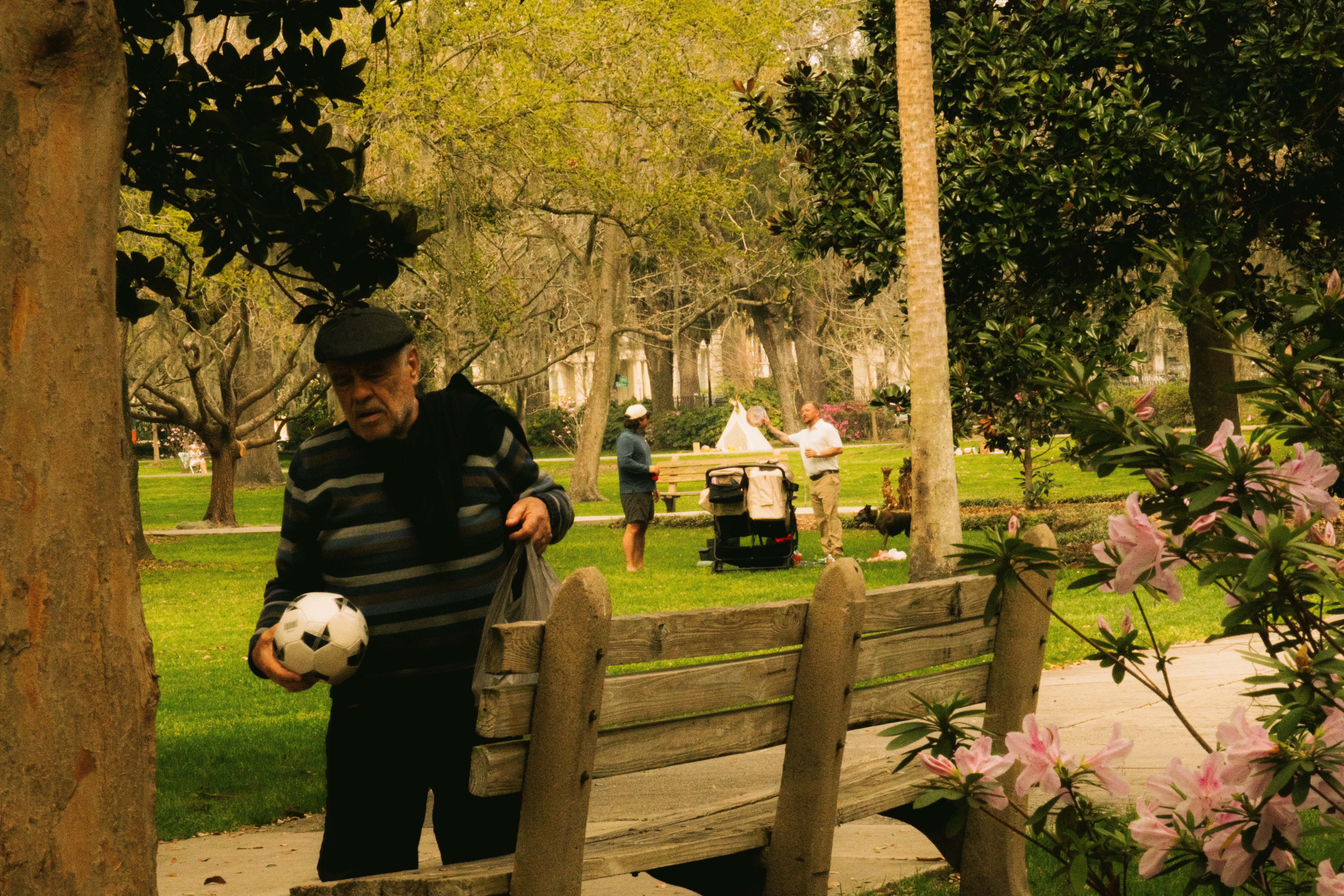 Older man with a soccer ball near a park bench
