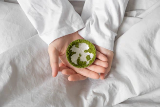 A person in a white long-sleeved shirt holding a small silver dish with green moss