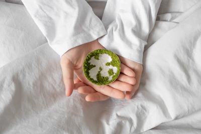 A person in a white long-sleeved shirt holding a small silver dish with green moss
