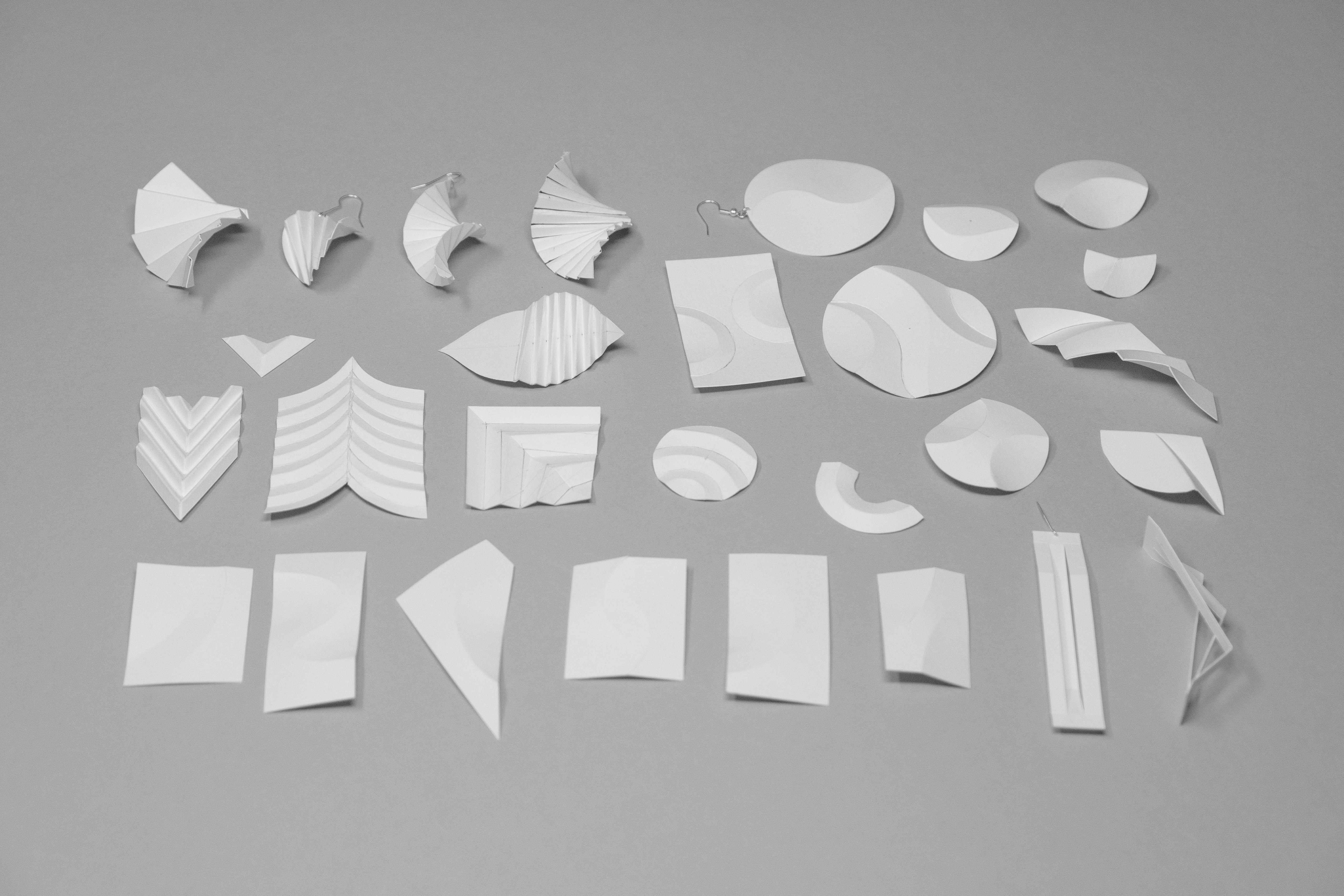 A collection of white paper shapes and folded forms on a grey surface
