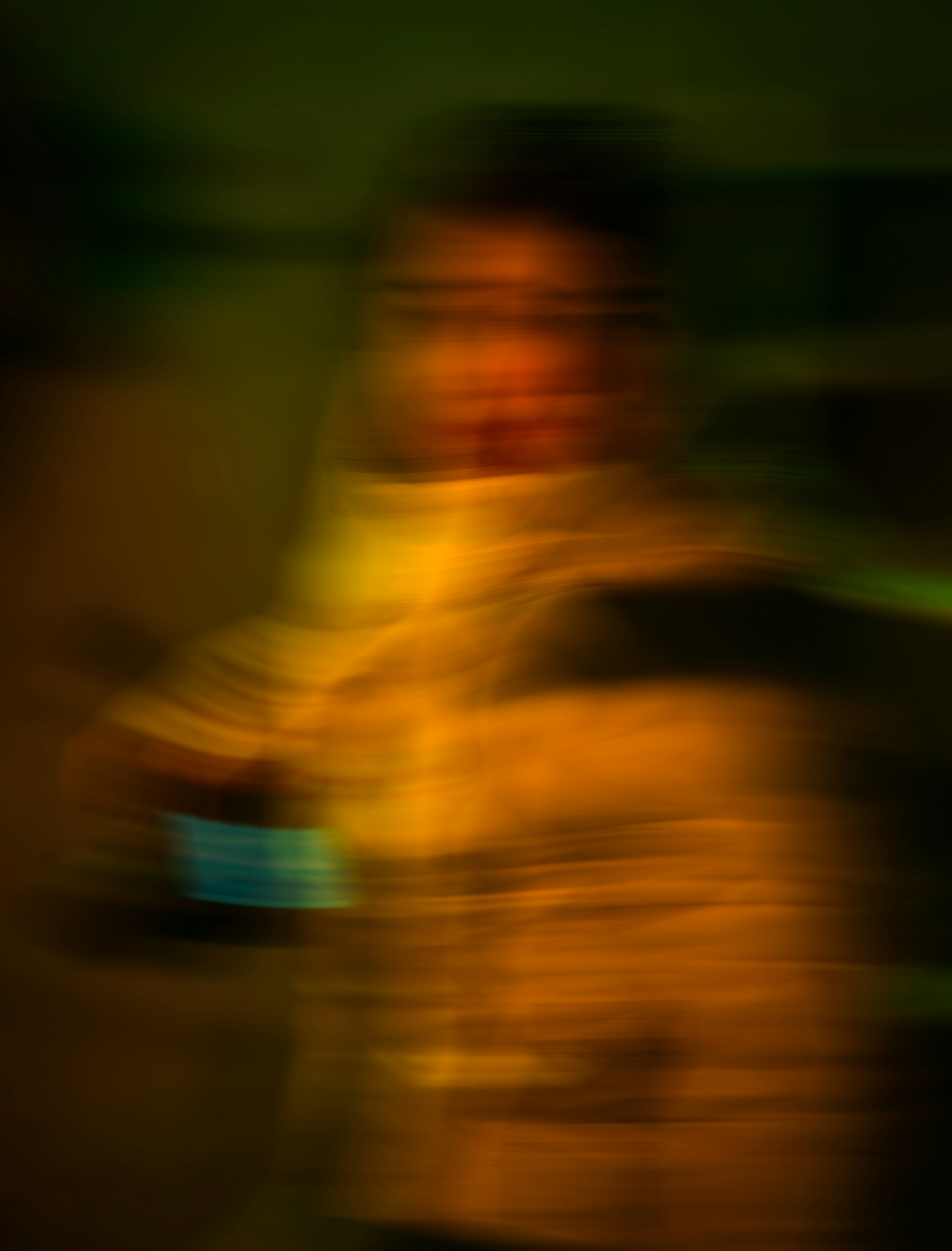 A person in a motion-blurred portrait with warm orange and green light