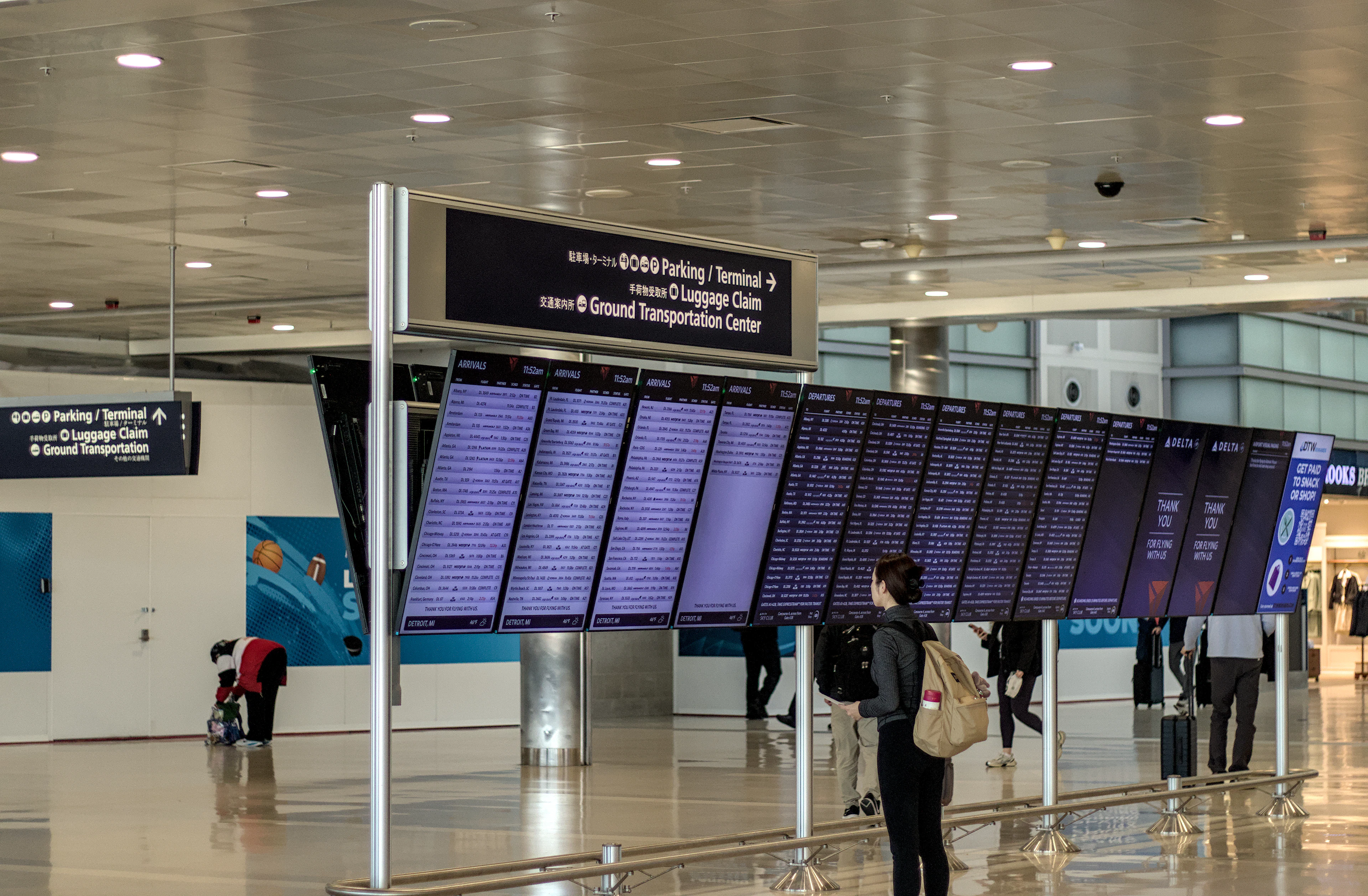 A traveller with a backpack checking the flight information boards in an airport terminal