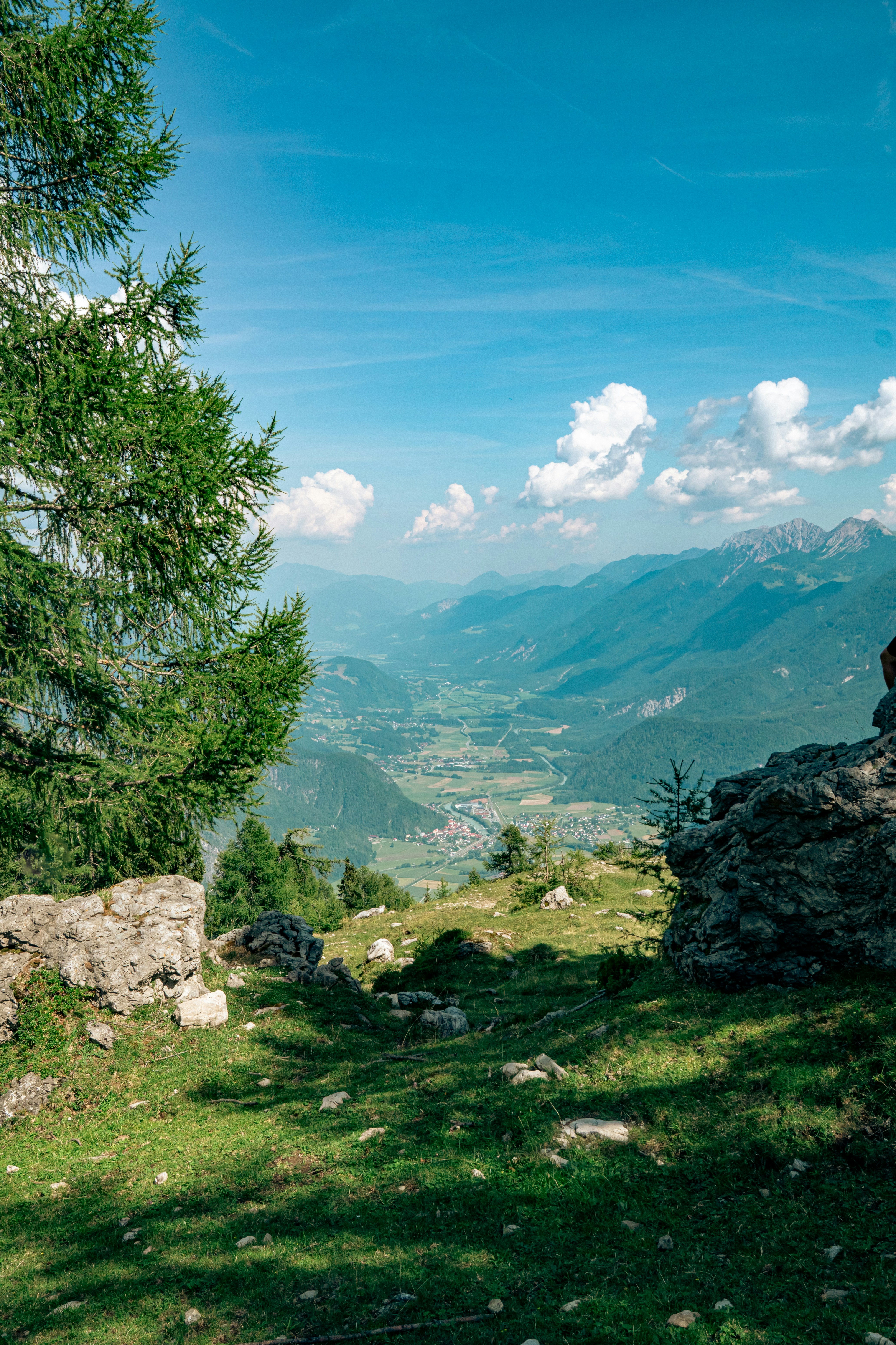 A view of a green valley and distant mountains from a rocky hillside