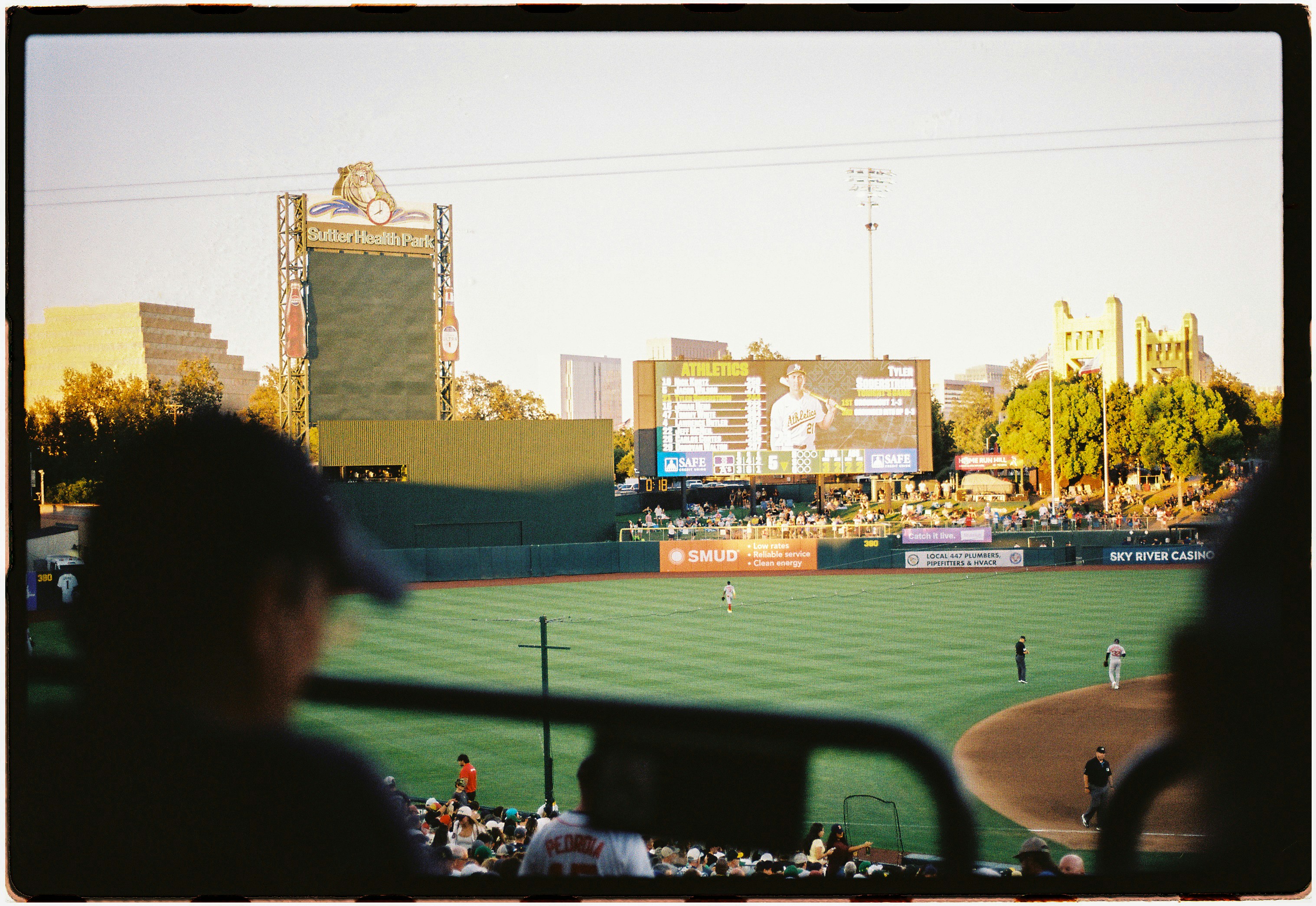 Um jogo de beisebol no Sutter Health Park, em Sacramento, com espectadores em primeiro plano