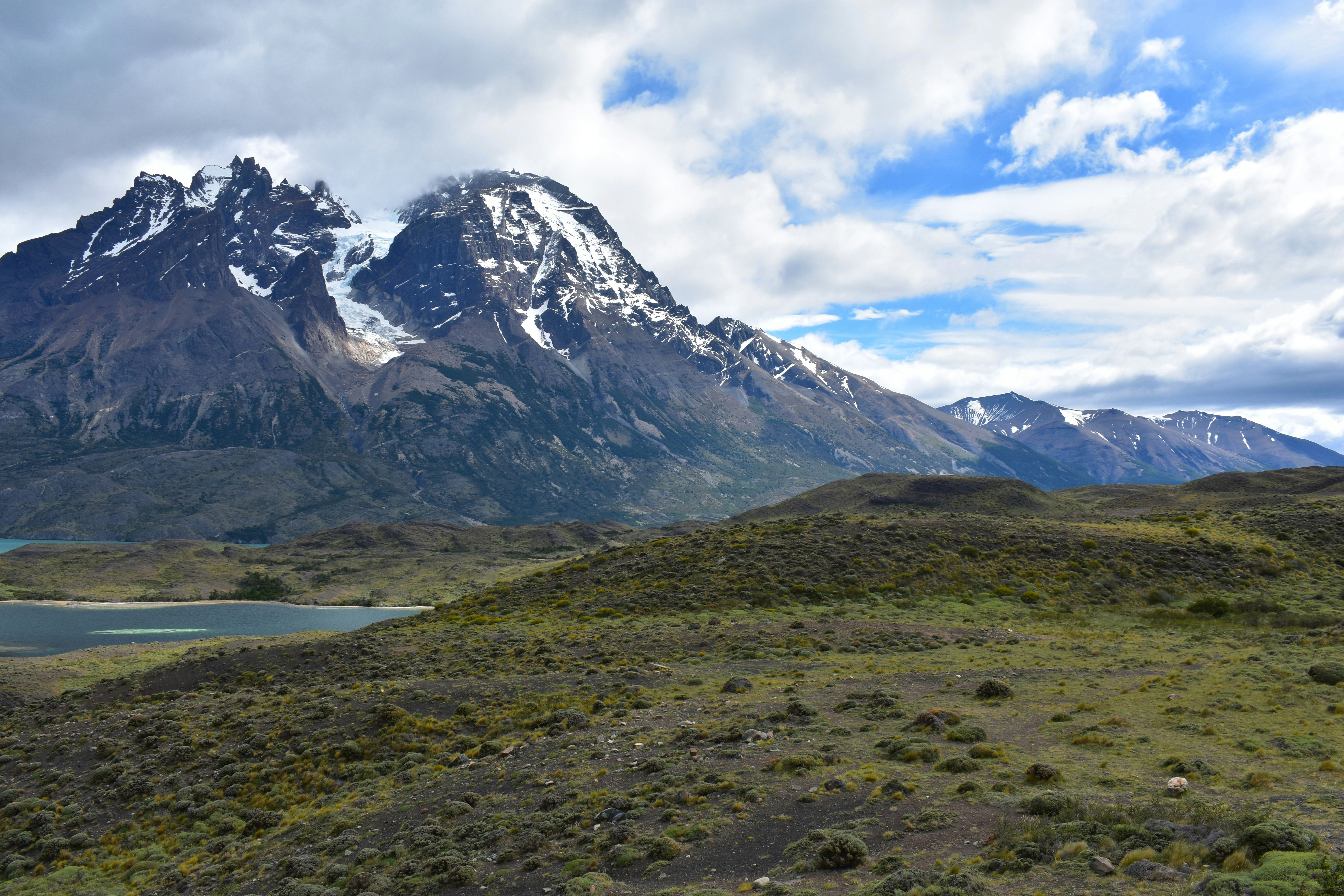 Snow-capped mountains rising above a green valley and a blue lake