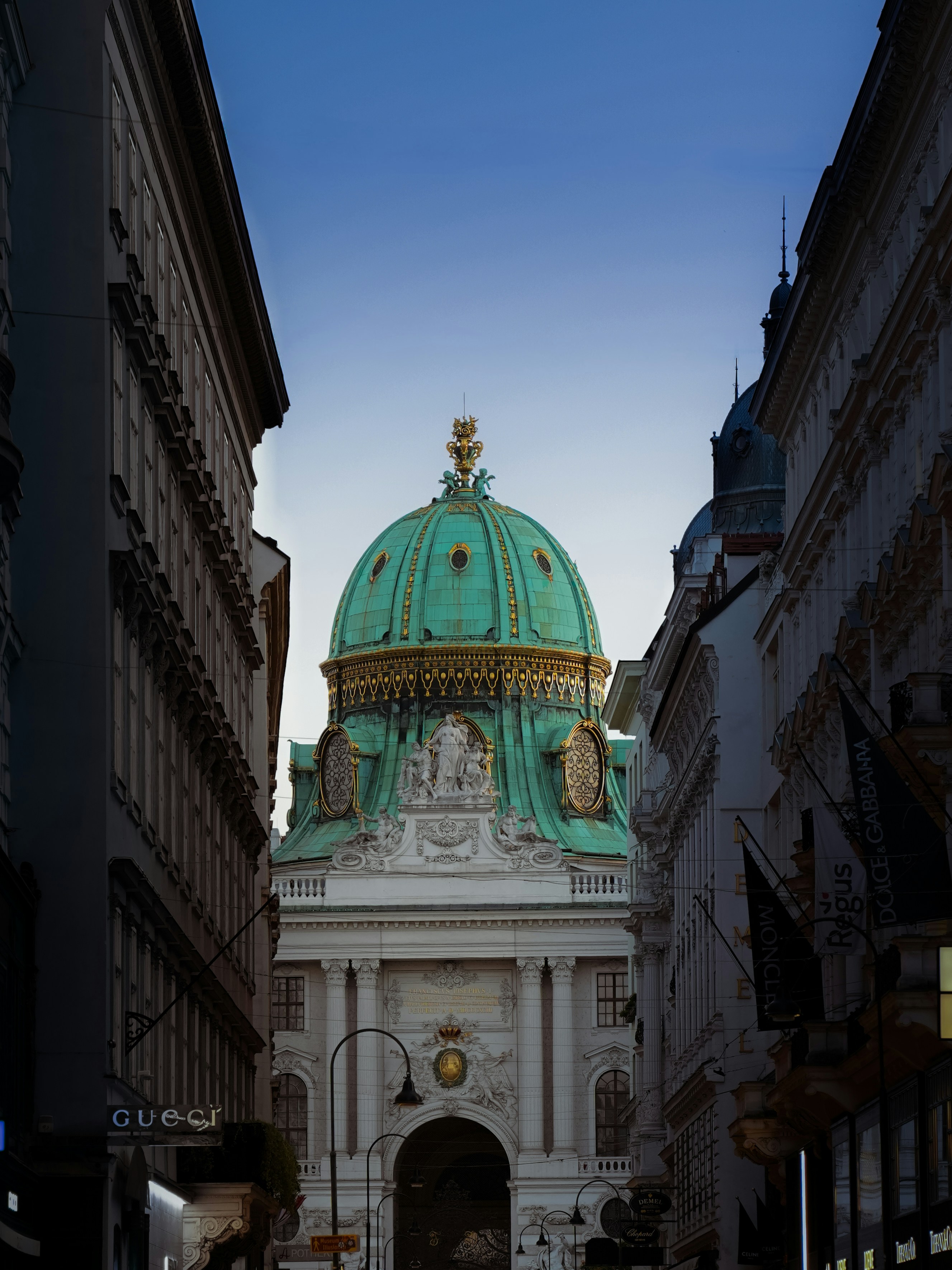 The green copper dome of the Hofburg Palace viewed from a narrow street in Vienna